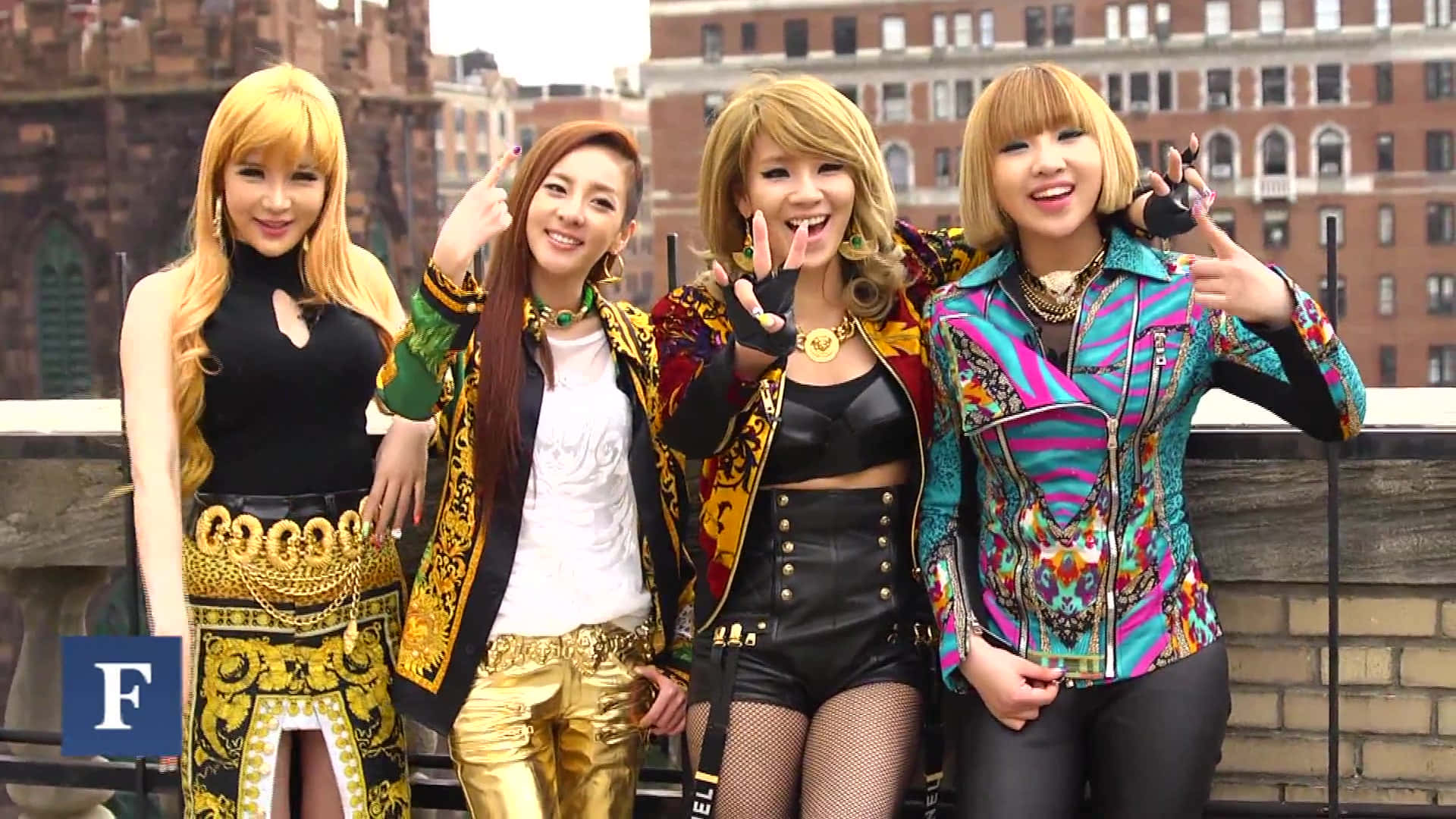 與2NE1一起搖擺 壁紙 — 四位時尚女性穿著大膽色彩繽紛的服裝，在磚砌建築背景的屋頂上愉快地擺姿勢。