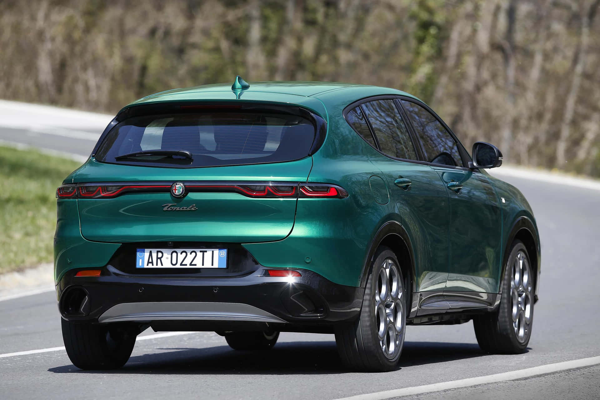 綠色Alfa Romeo Tonale SUV喺森林道路上行駛。