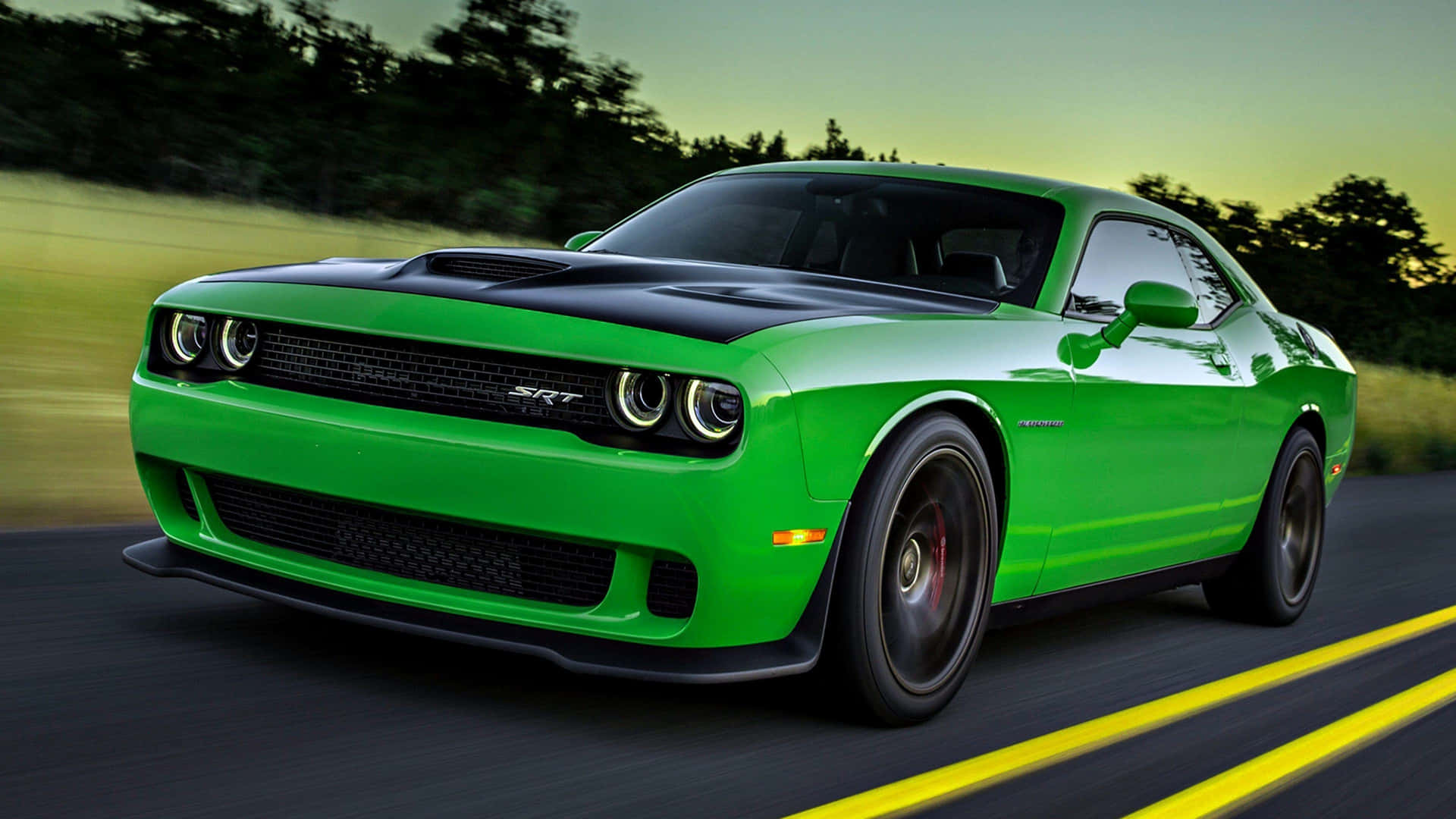 綠色 Dodge Challenger SRT 在日落時分的道路上疾馳。