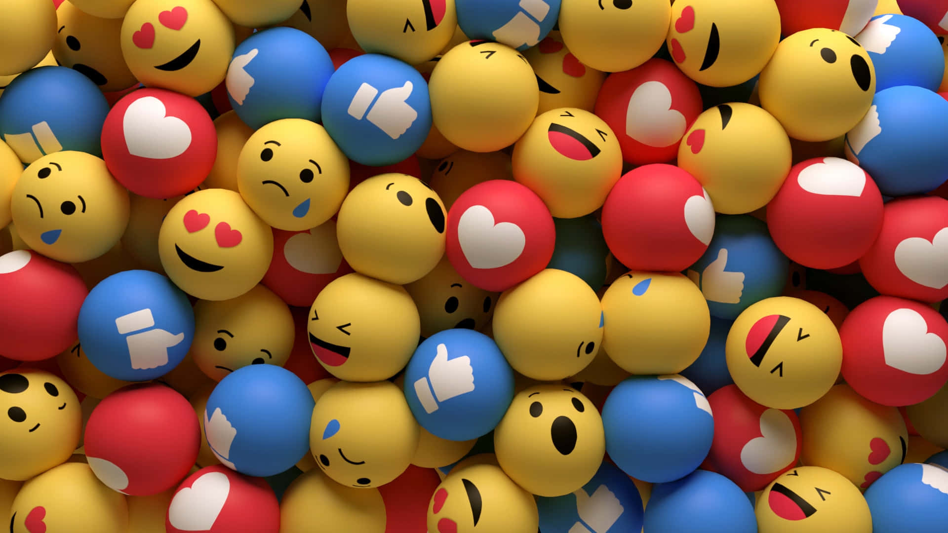 與Emoji一起玩樂 壁紙 — 一堆色彩鮮豔、光滑的黃色、紅色和藍色表情符號球，展示愛心、豎起大拇指和笑臉。
