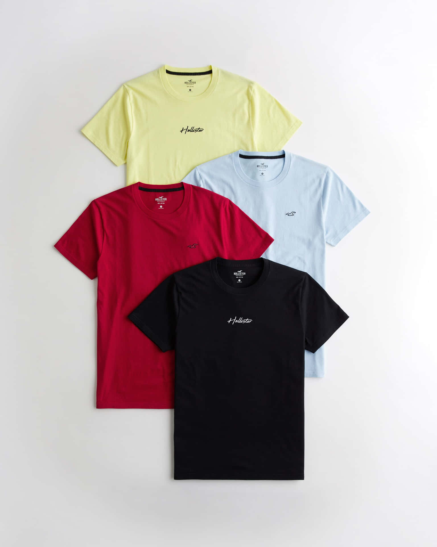 四件Hollister T恤，紅色、黃色、淺藍色和黑色，平放在白色背景上展示。