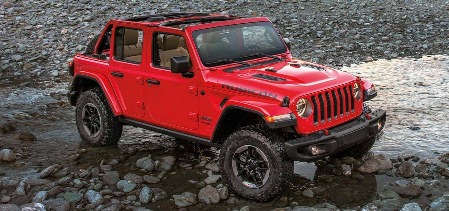 紅色Jeep Wrangler Rubicon駛過淺石溪。