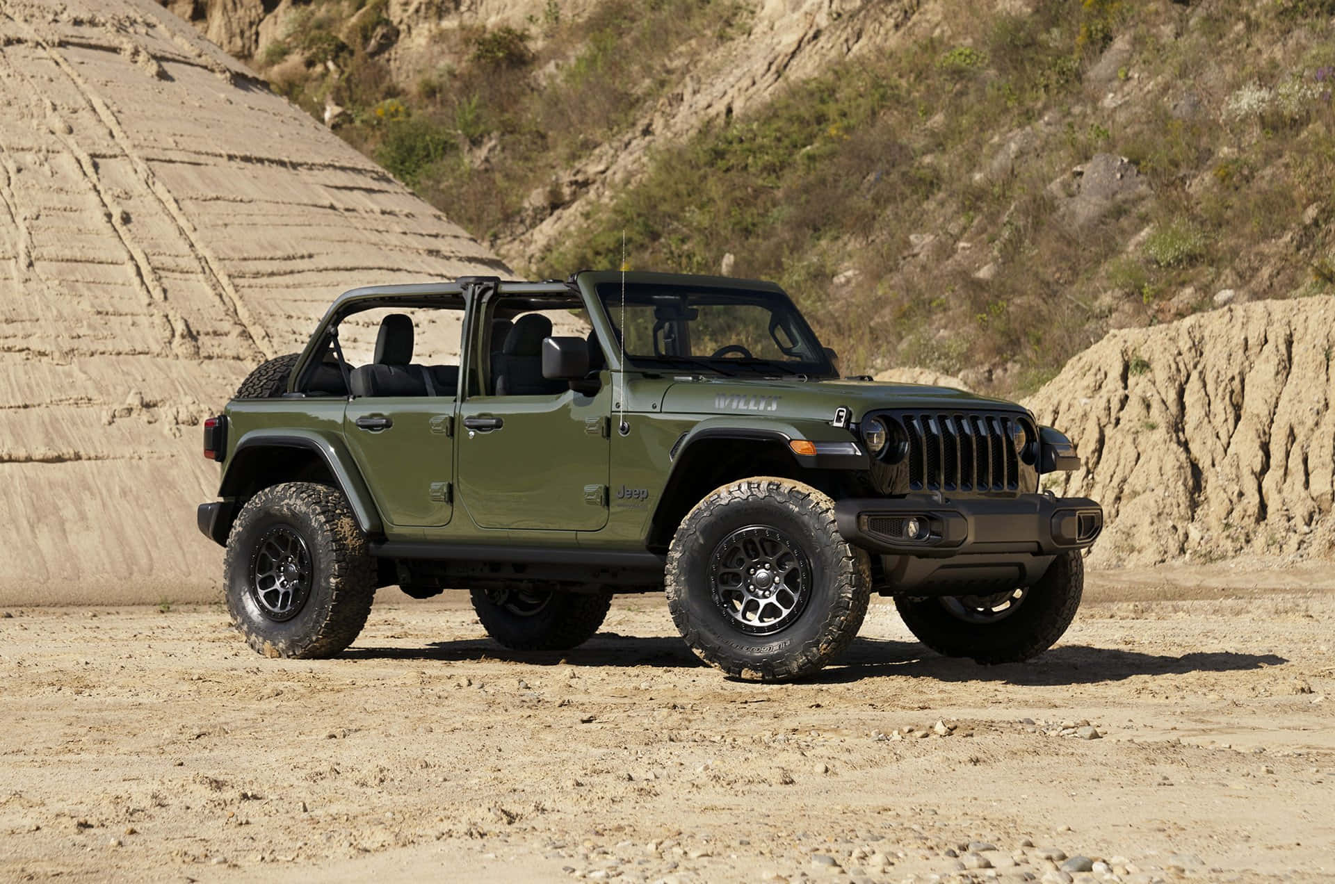 橄欖綠色Jeep Wrangler停在岩石結構附近的泥土上