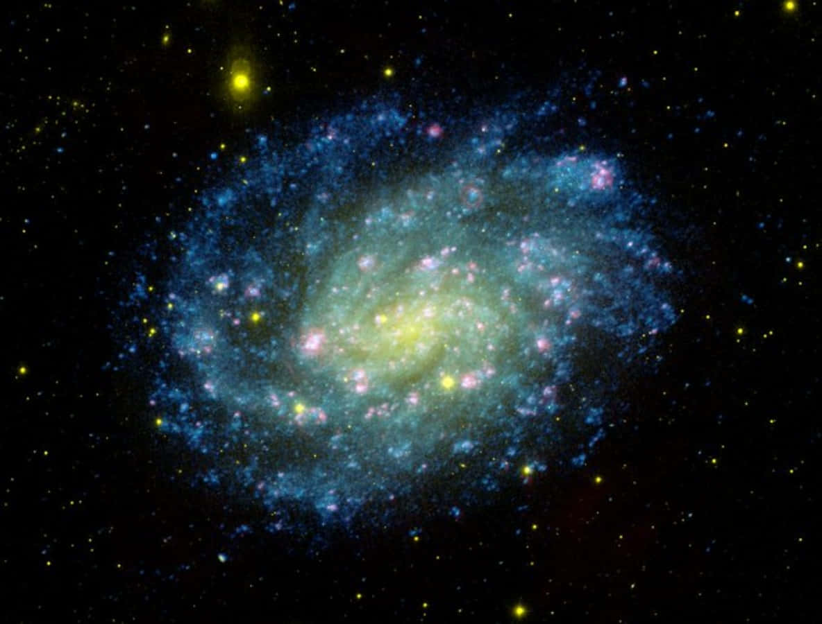 與NASA星系一同探索深空 壁紙 — 一個充滿活力的螺旋星系，在星空背景下旋轉著藍色和黃色的色調。