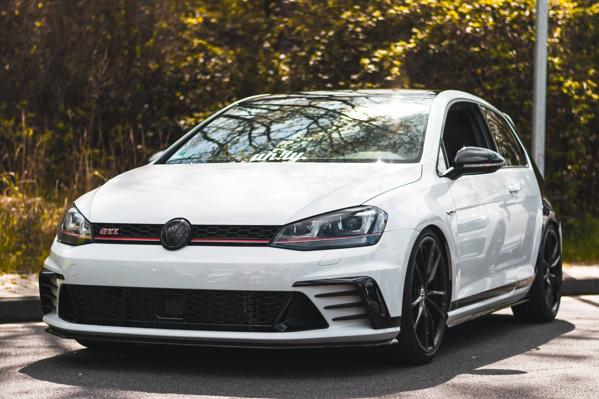 白色 Volkswagen Golf GTI 在陽光明媚的日子停放在戶外。
