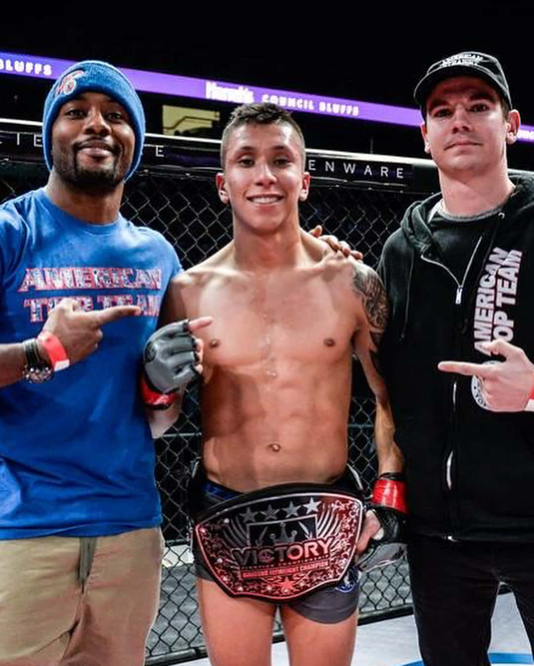 三名男子慶祝MMA勝利，一名拳手手持冠軍腰帶。