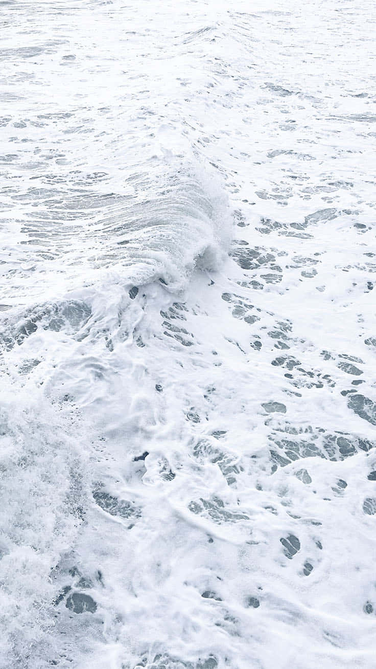 泡沫海浪翻滾而來，帶有紋理的白泡沫和灰藍色海水。
