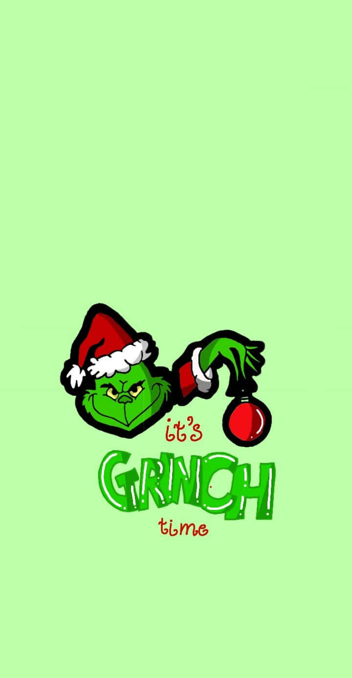 戴住聖誕帽嘅鬼靈精拎住紅色裝飾，上面有文字 it's GRINCH time。