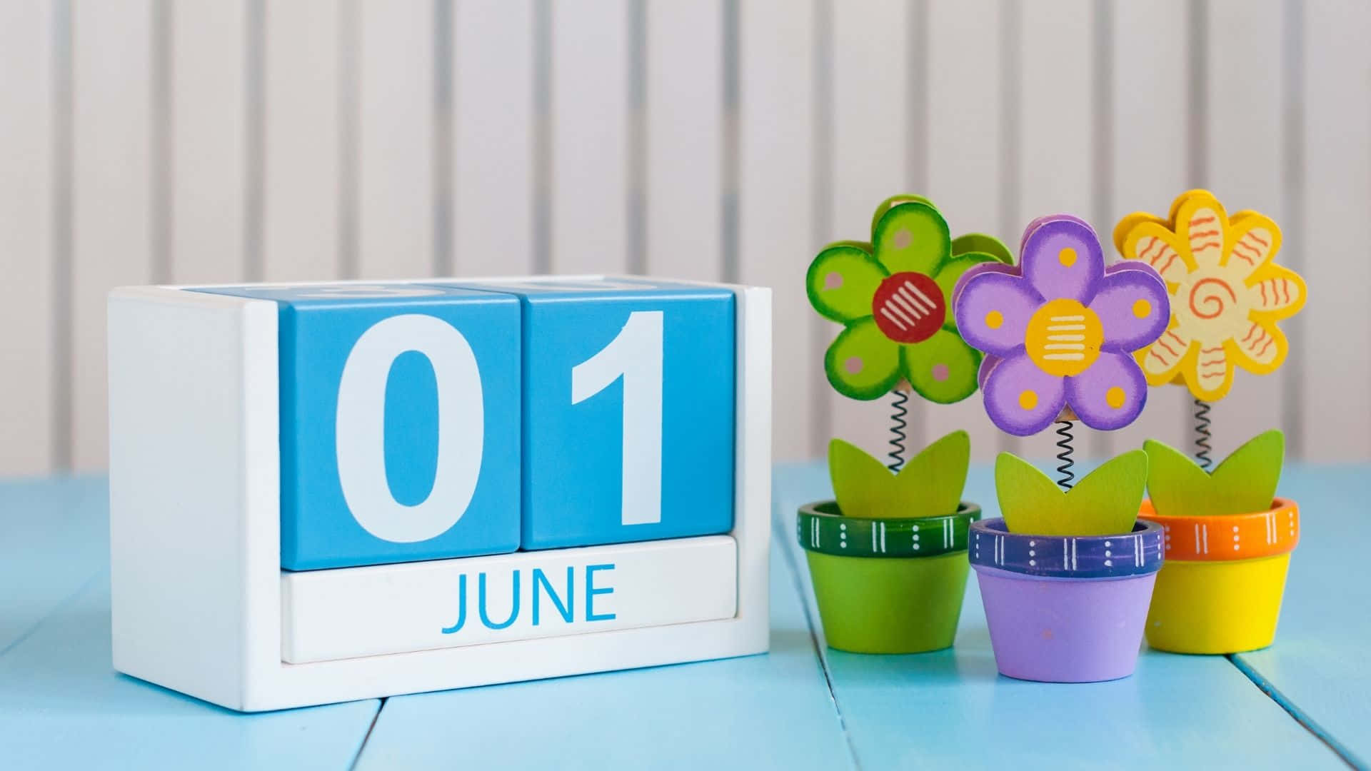 6月1日日曆塊與藍色木桌上的彩色玩具花盆。