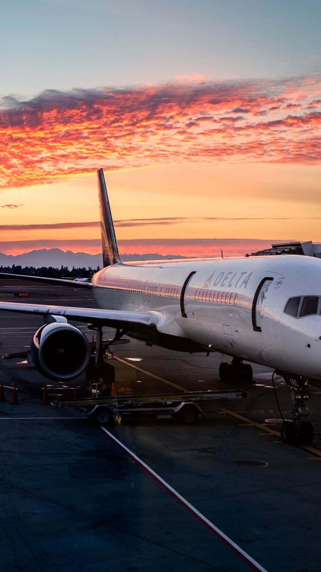 達美航空飛機在停機坪上，背景是鮮豔的日落和山巒