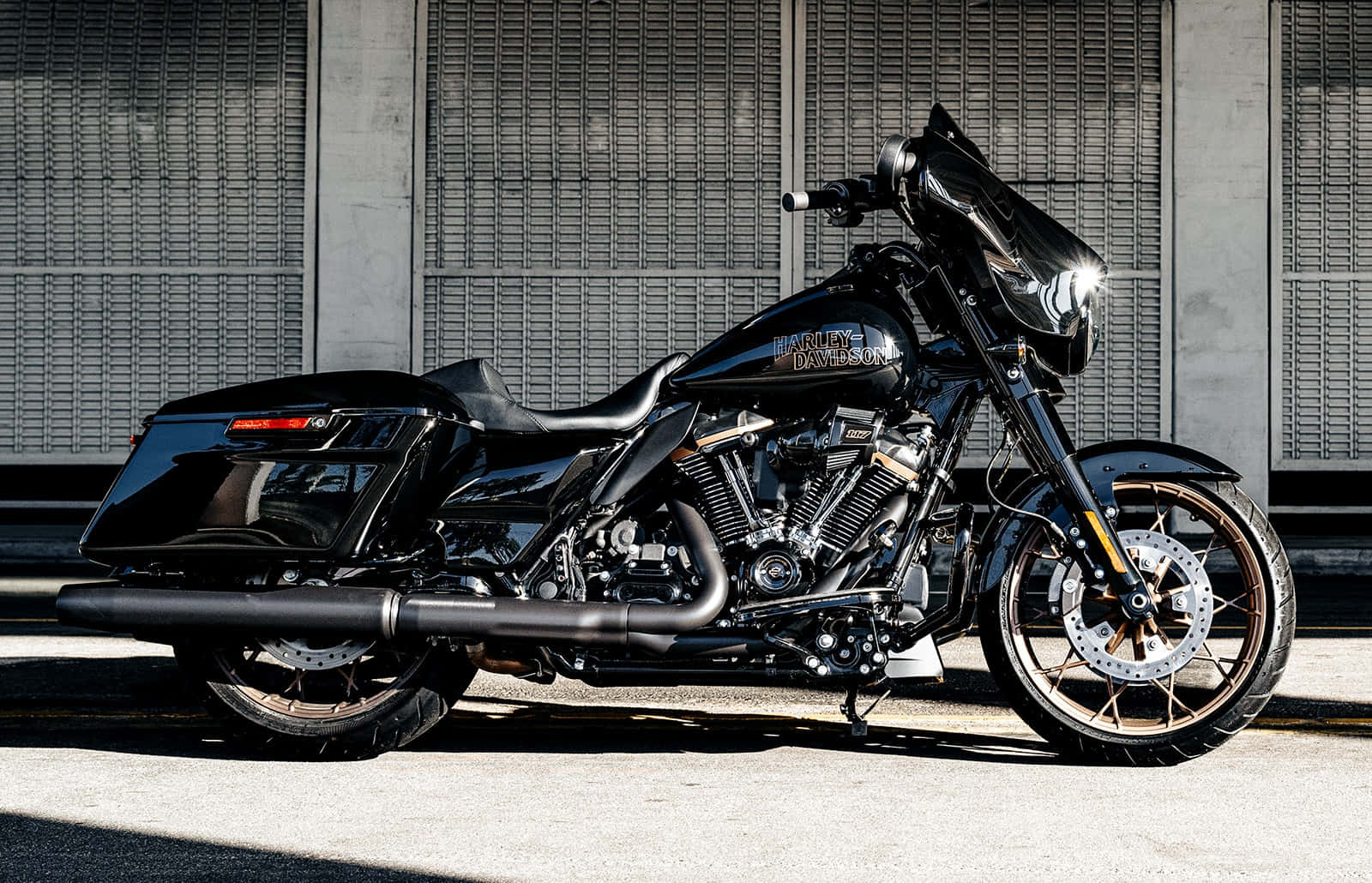 黑色Harley-Davidson電單車停泊在工業牆附近的行人路上。