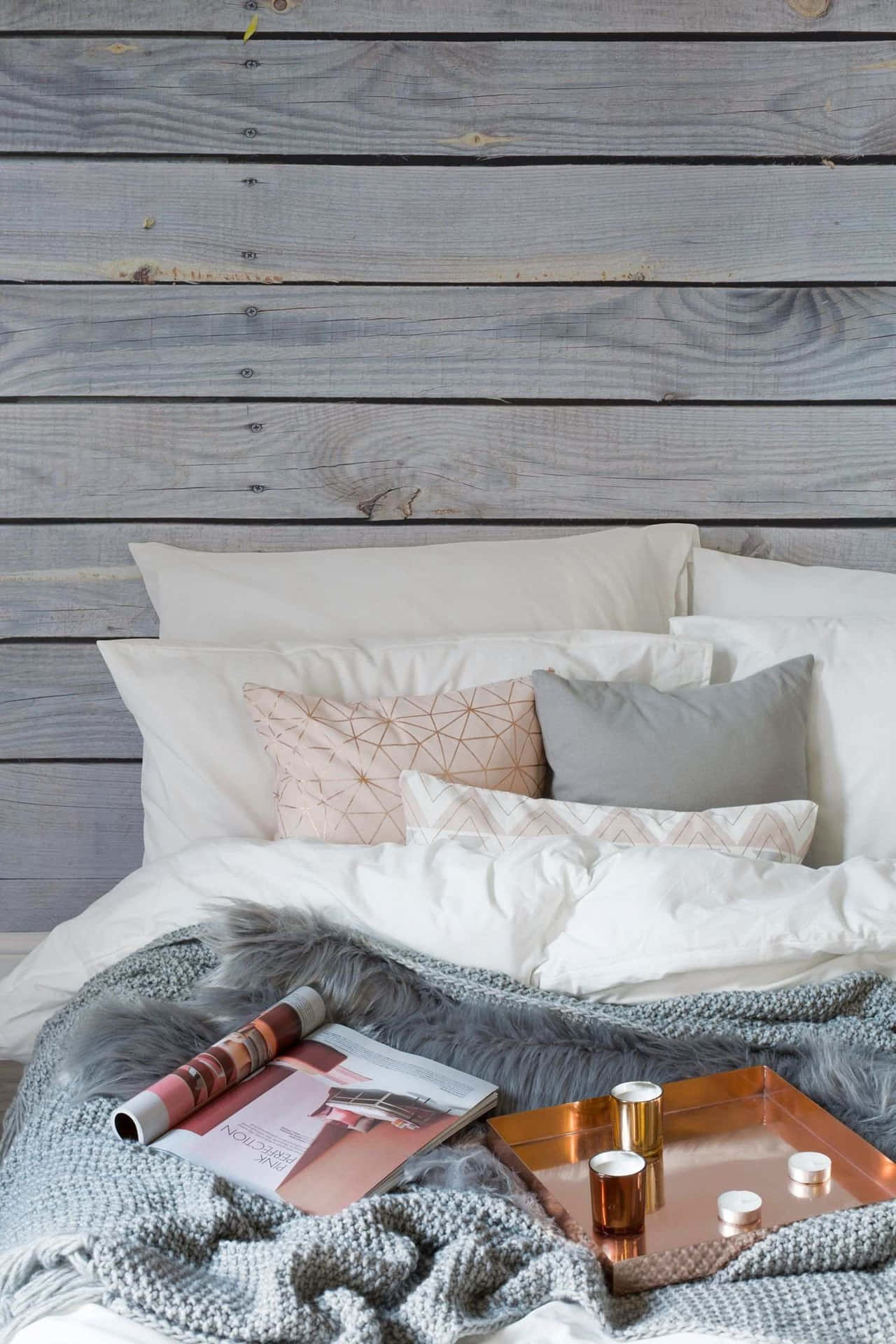 舒適的床，配有灰色毯子和銅托盤，靠著木牆。