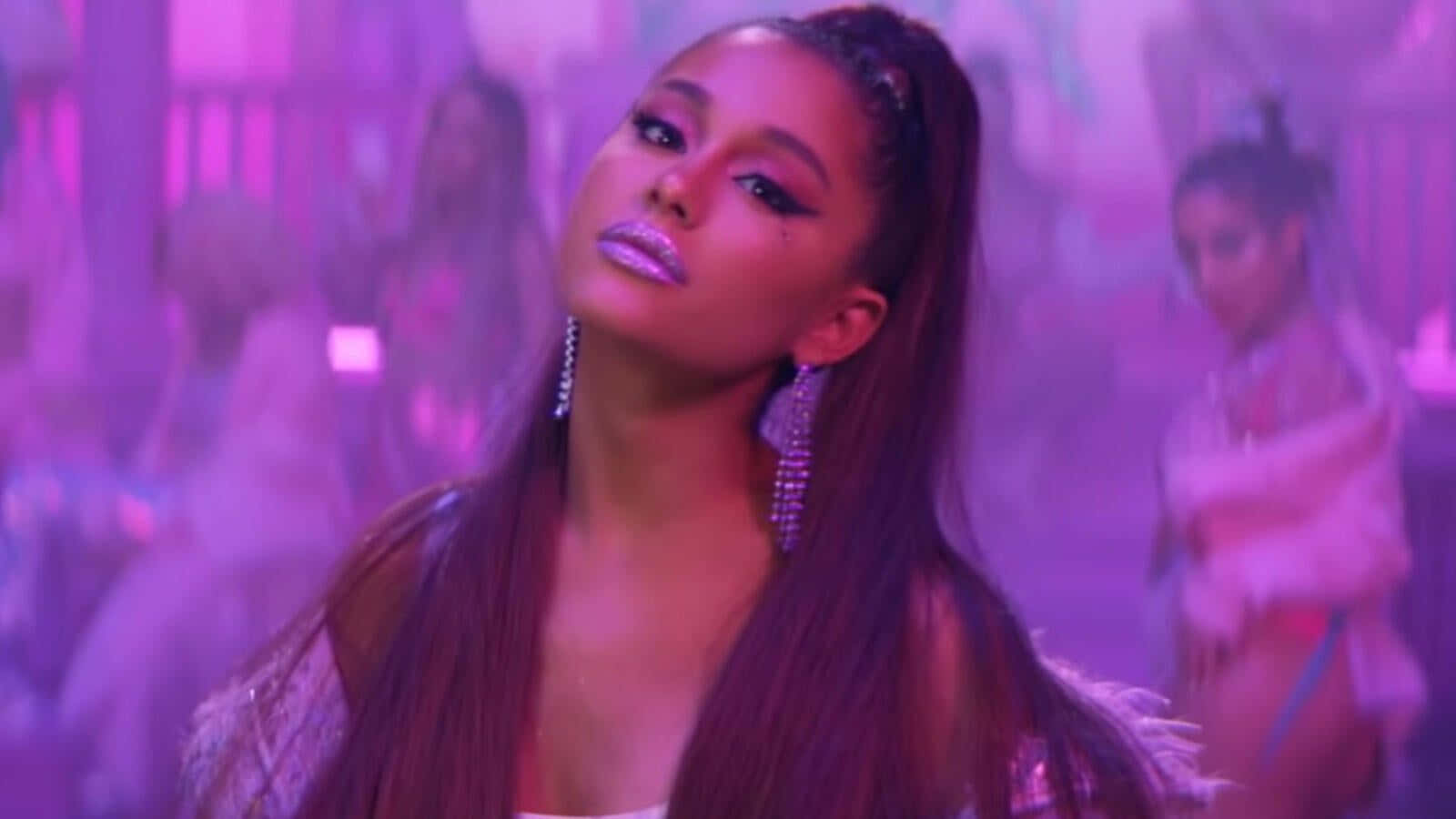 Ariana Grande 在紫色燈光舞台上表演，身後有舞者。