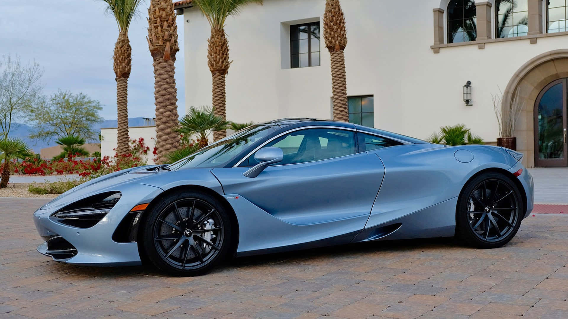 銀色McLaren 720S停泊在帶有棕櫚樹的豪宅前。