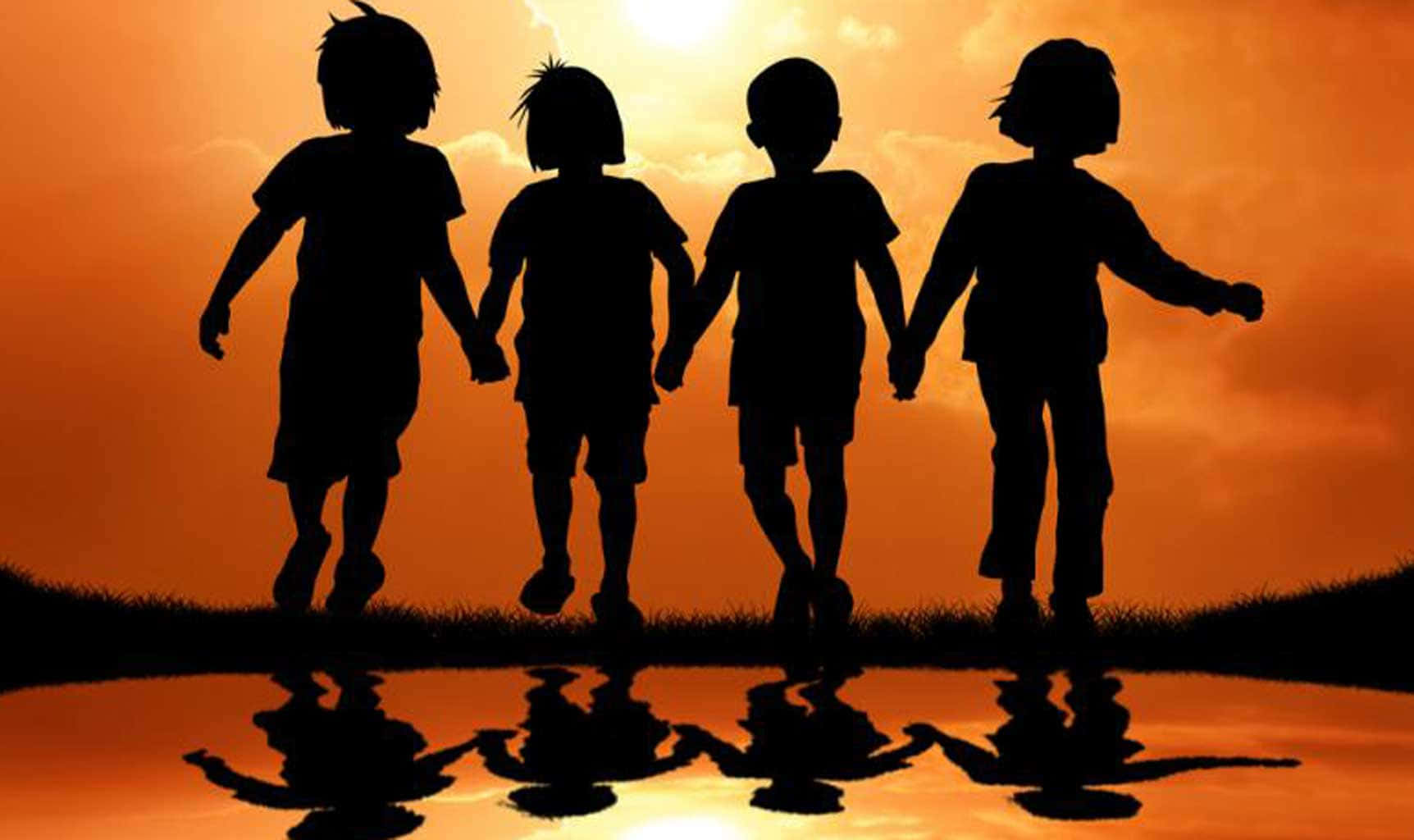 四個小孩手牽手在夕陽下的水坑中跳躍。