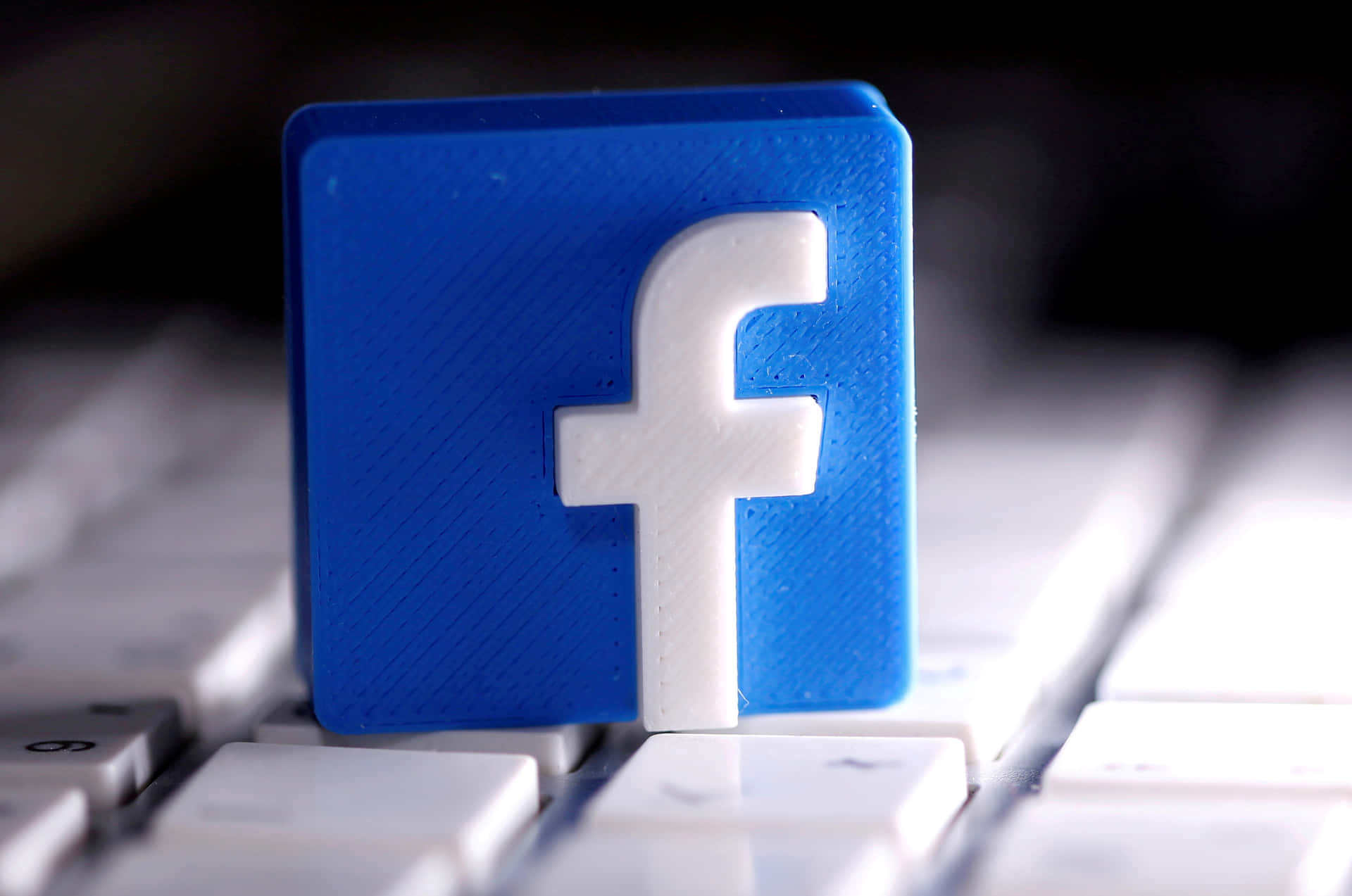 白色鍵盤上的藍色3D打印Facebook標誌立方體