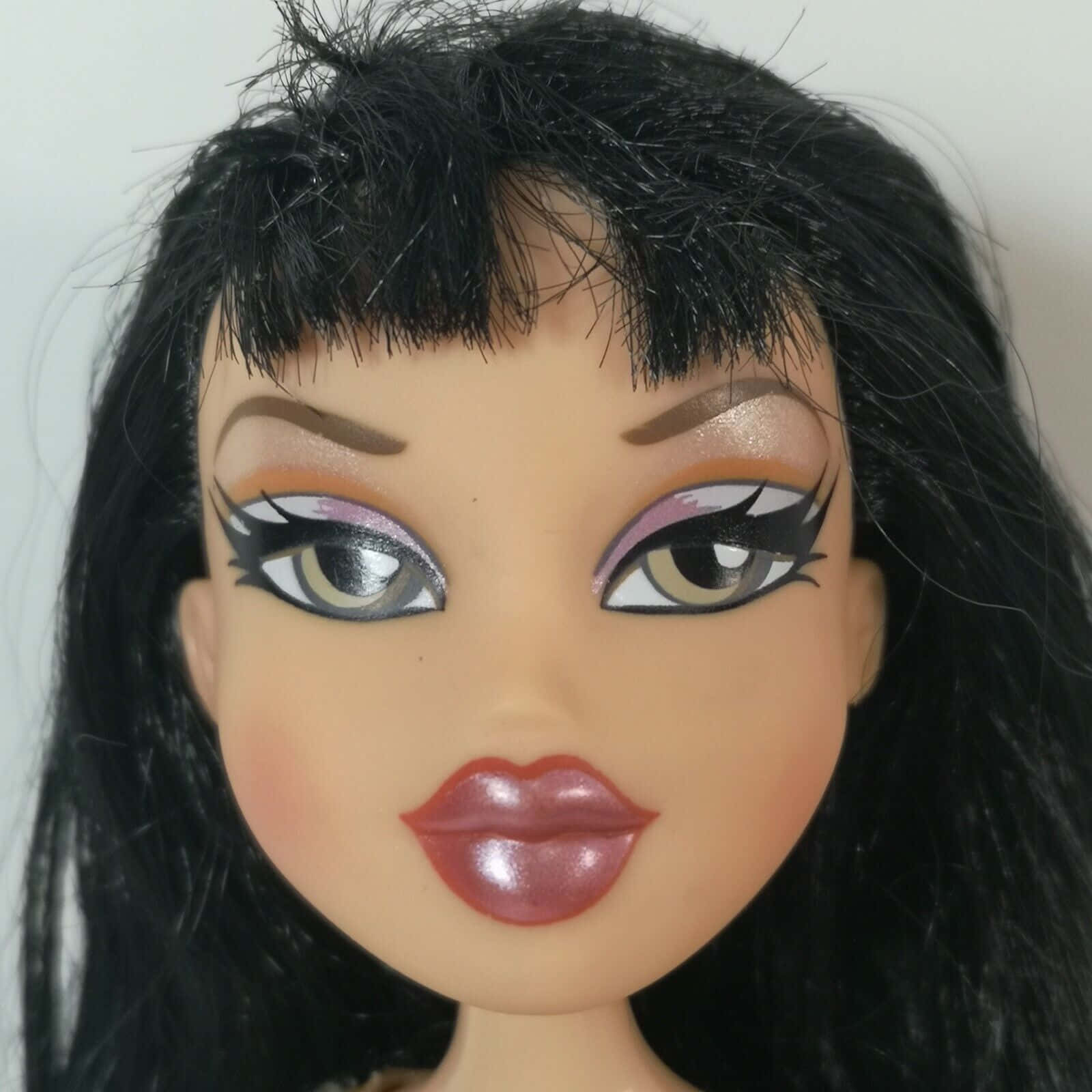 與朋友共度歡樂時光，展現你的Bratz風格！ 壁紙 — Bratz 公仔嘅特寫，有誇張化妝、黑色頭髮同光澤嘴唇，背景係純色。