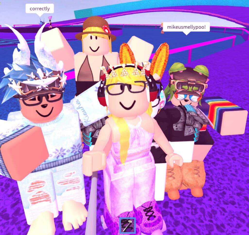 與朋友在Roblox中創造永恆回憶！ 壁紙 — 四個色彩繽紛的Roblox虛擬角色，穿著獨特的服裝和配飾，在充滿活力的紫色數位環境中一起擺姿勢。
