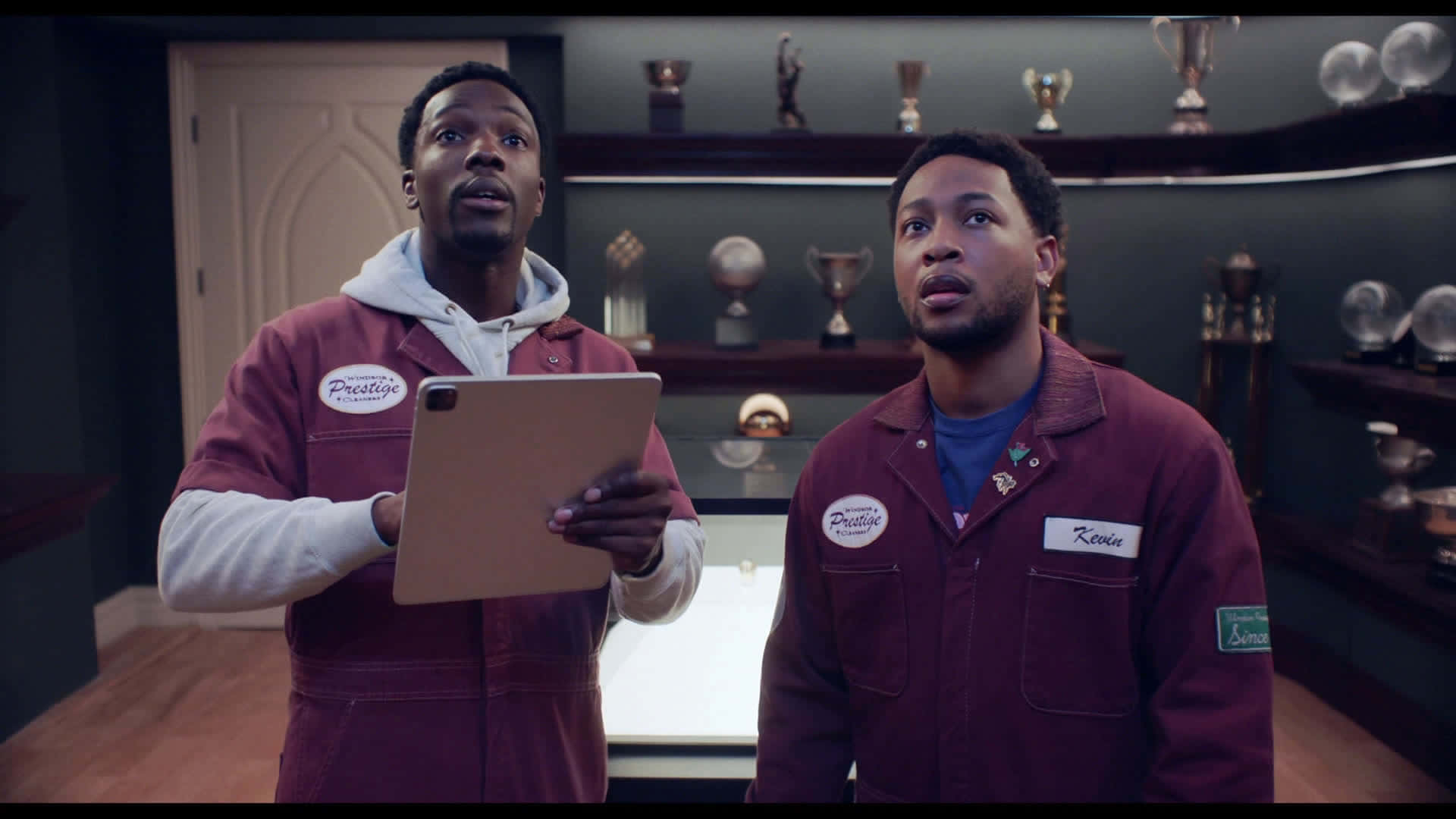 兩名身穿栗色外套的男子在獎盃室裡抬頭看。