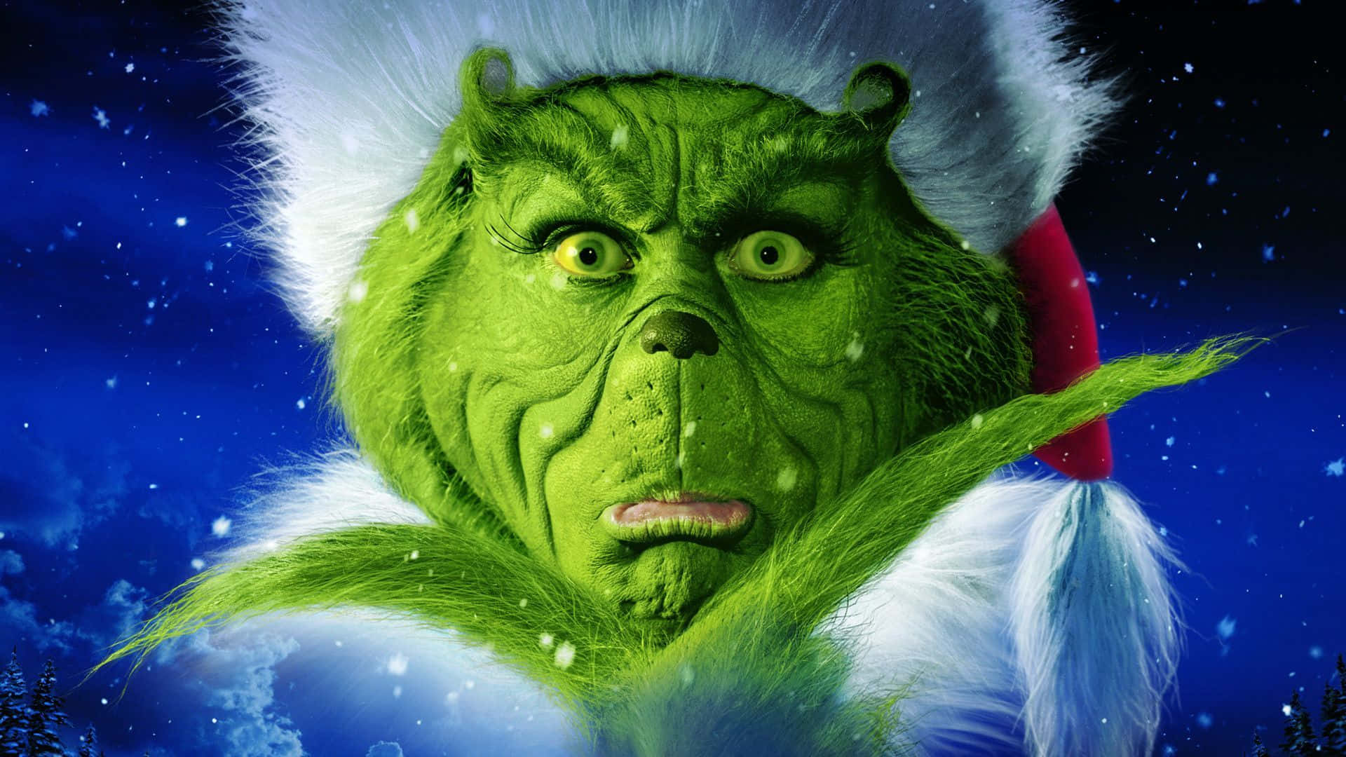 戴著聖誕帽的鬼靈精（Grinch）憤怒地望著飄雪的夜空