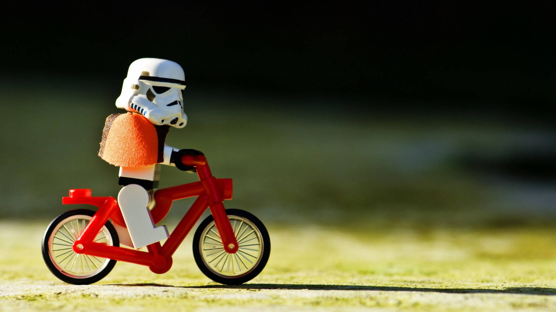 LEGO風暴兵在陽光下在草地上騎著一輛紅色單車。