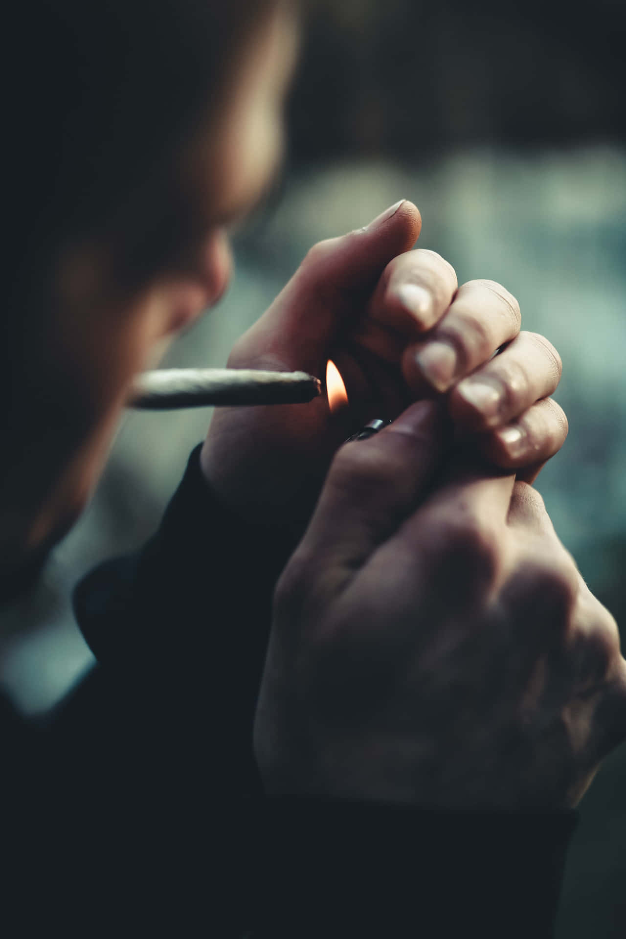 一個人在昏暗光線下用打火機點燃香煙。