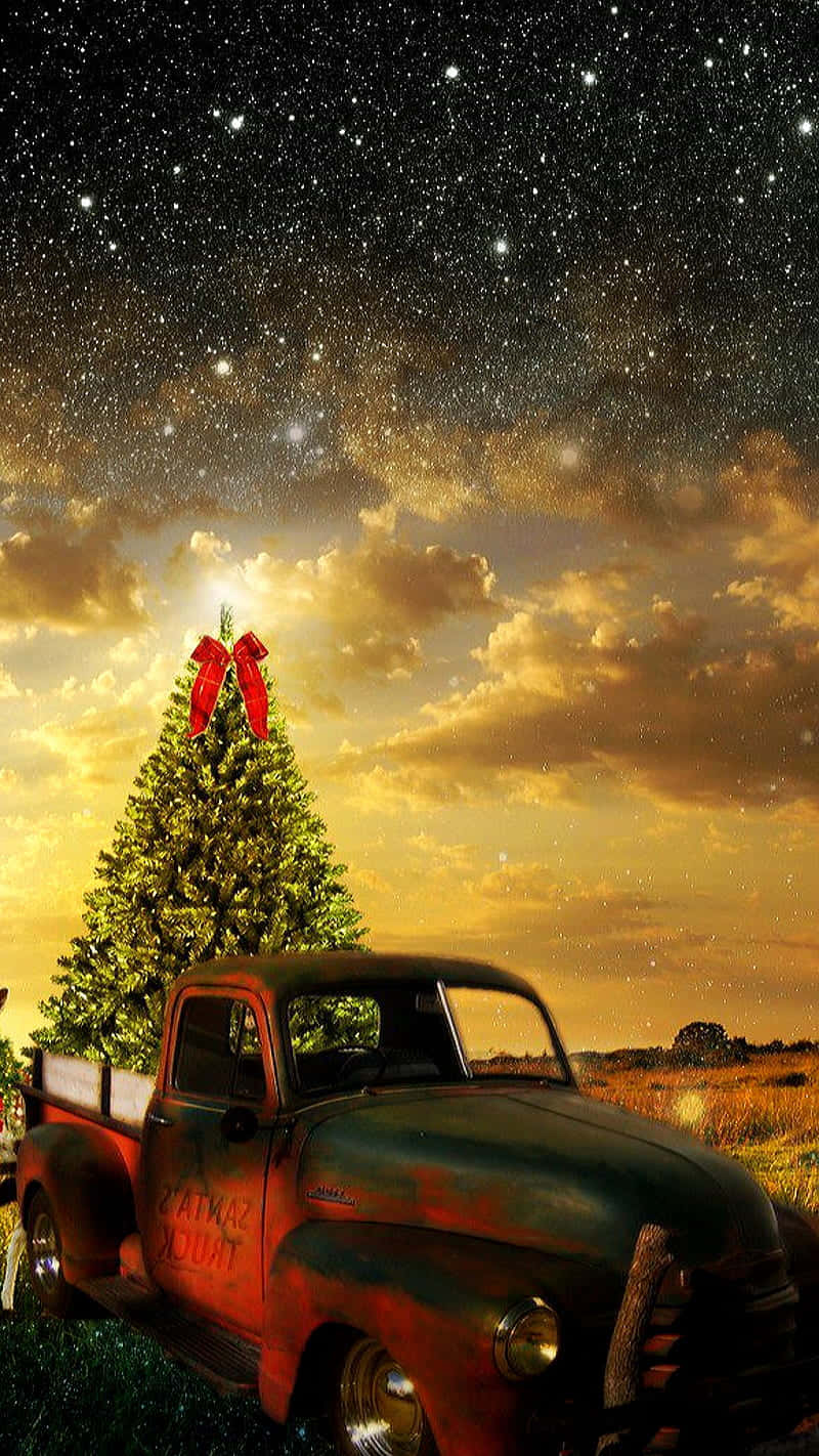 與聖誕主題老式卡車一同慶祝節日 壁紙 — 一輛復古生鏽卡車在星光燦爛的暮色天空下運送聖誕樹，天空中有金色的雲彩。