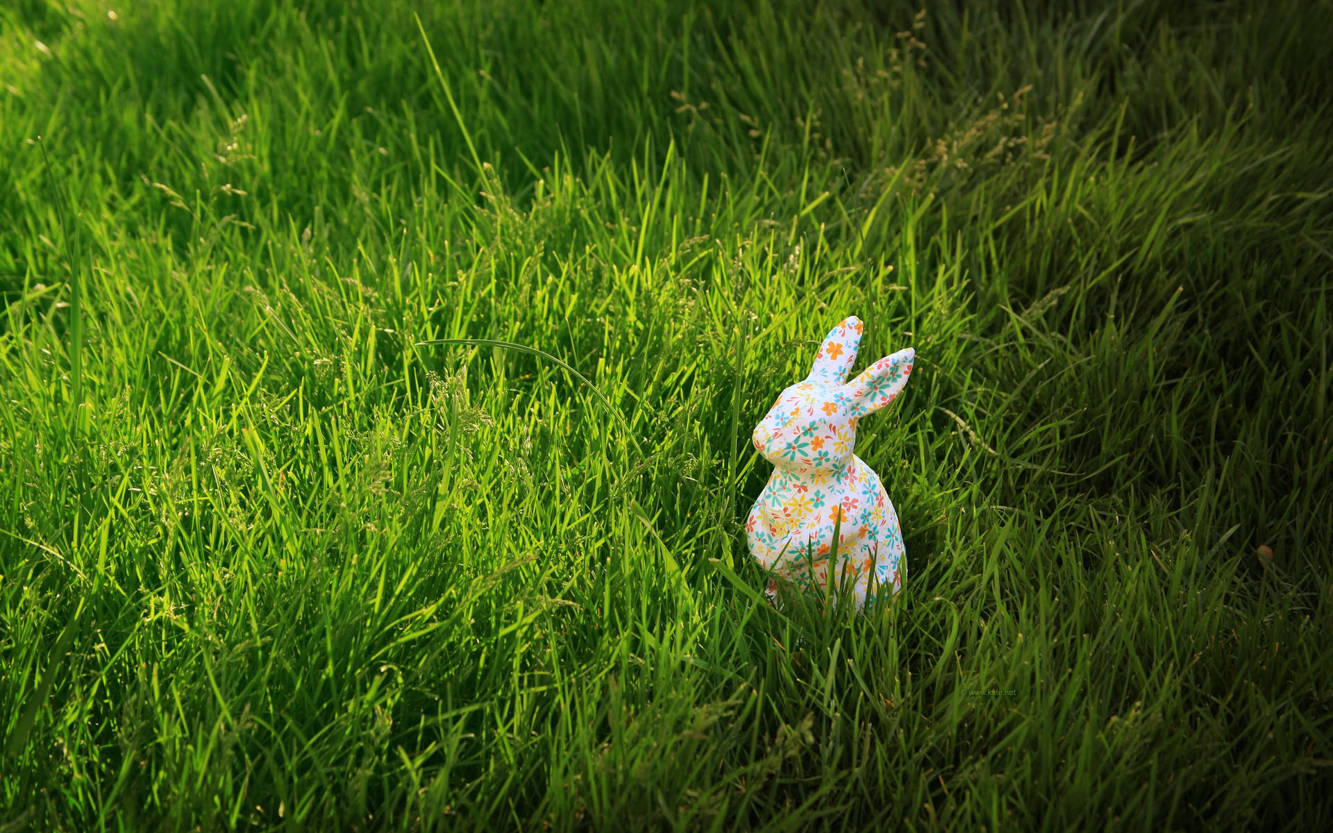 陽光明媚的日子裡，綠草如茵中的花卉陶瓷兔子公仔。