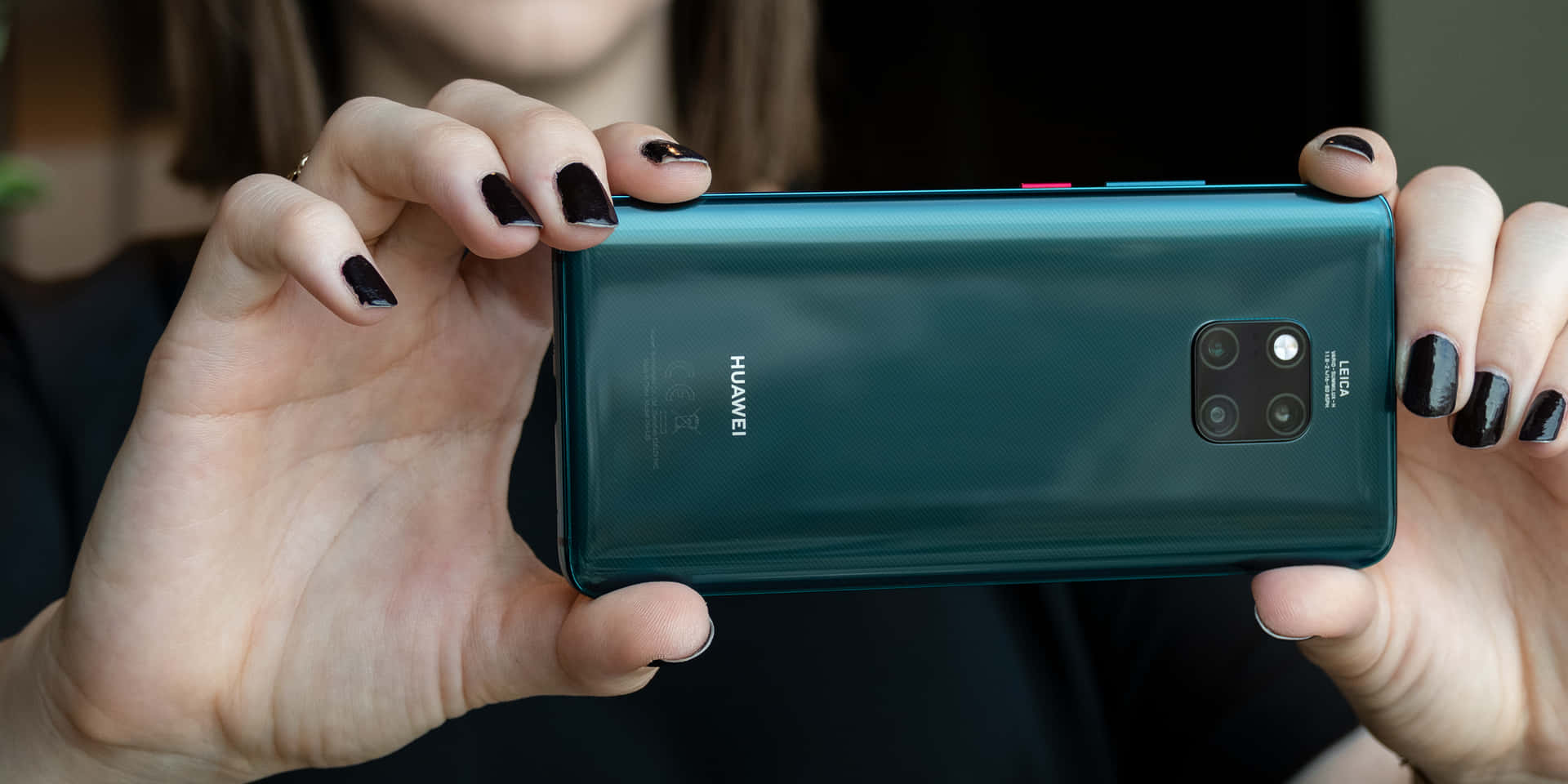 手持青綠色Huawei四鏡頭智能手機的特寫。