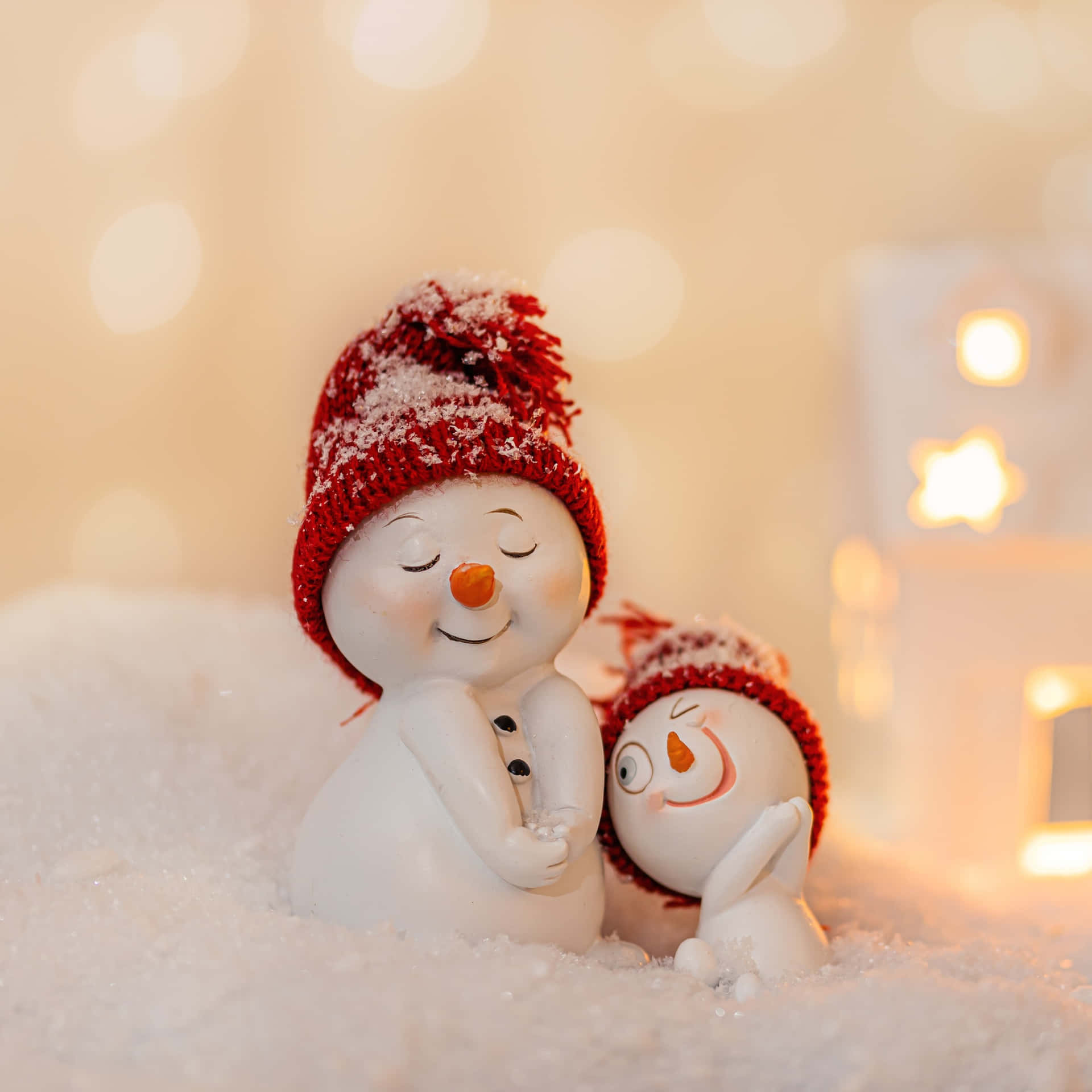 兩個雪人公仔在雪中擁抱，身後有溫暖的燈光。