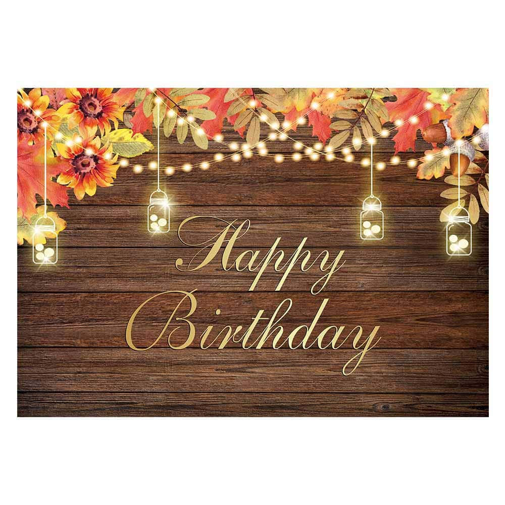 木製背景上帶有秋葉和串燈的Happy Birthday標誌。
