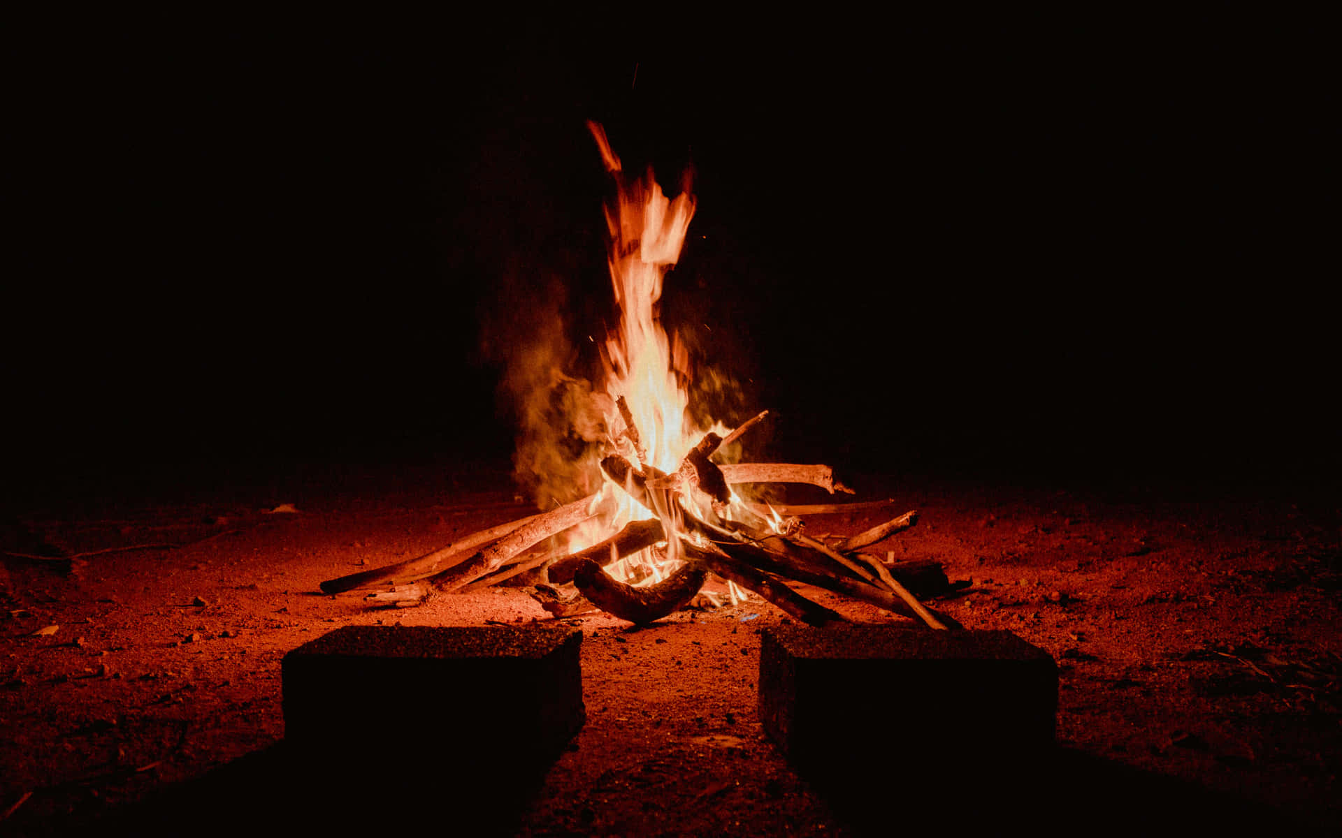夜晚燃燒的明亮營火，帶有發光的餘燼和周圍的泥土。