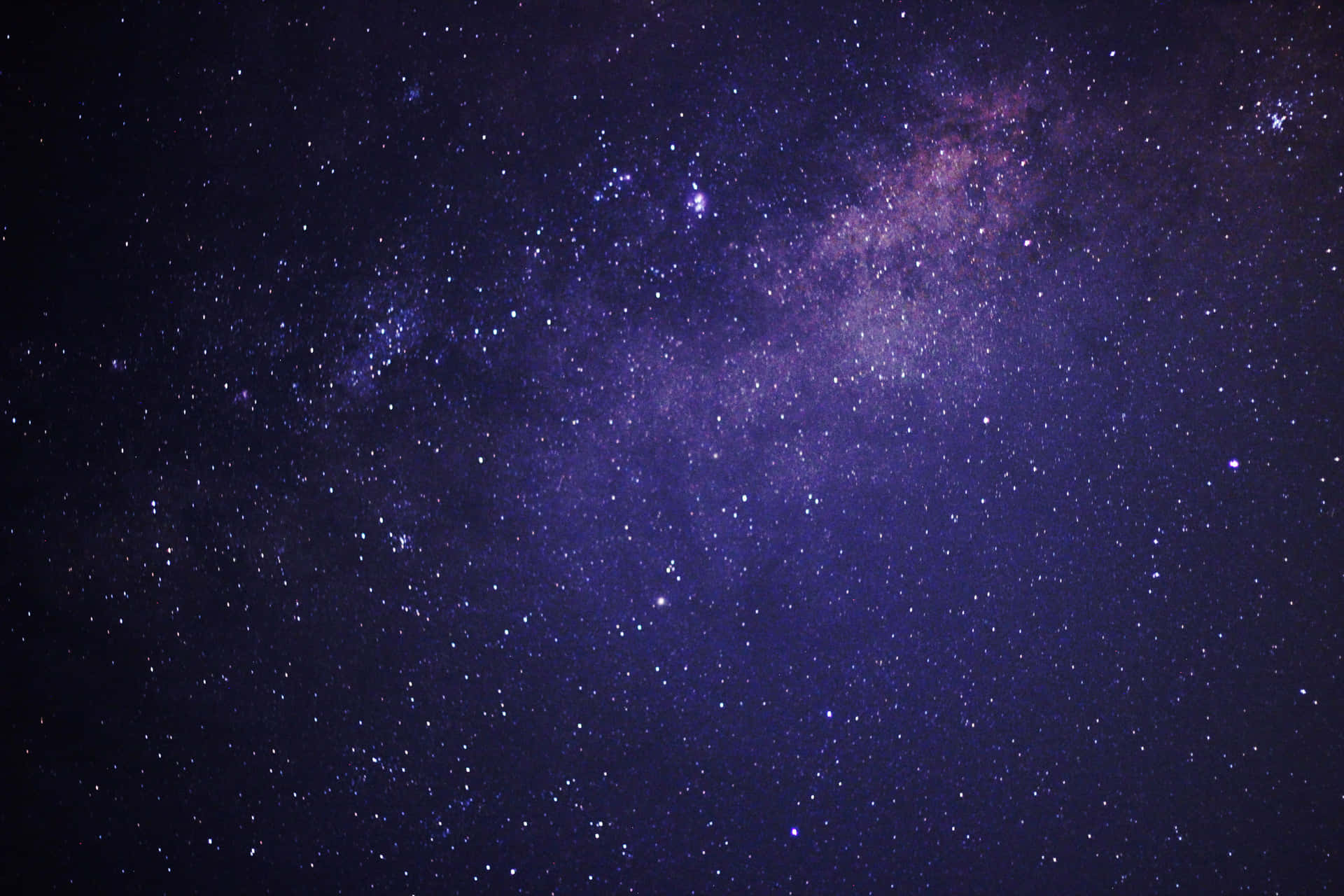 銀河系在佈滿星星的夜空中散發出深紫色和藍色的光芒。