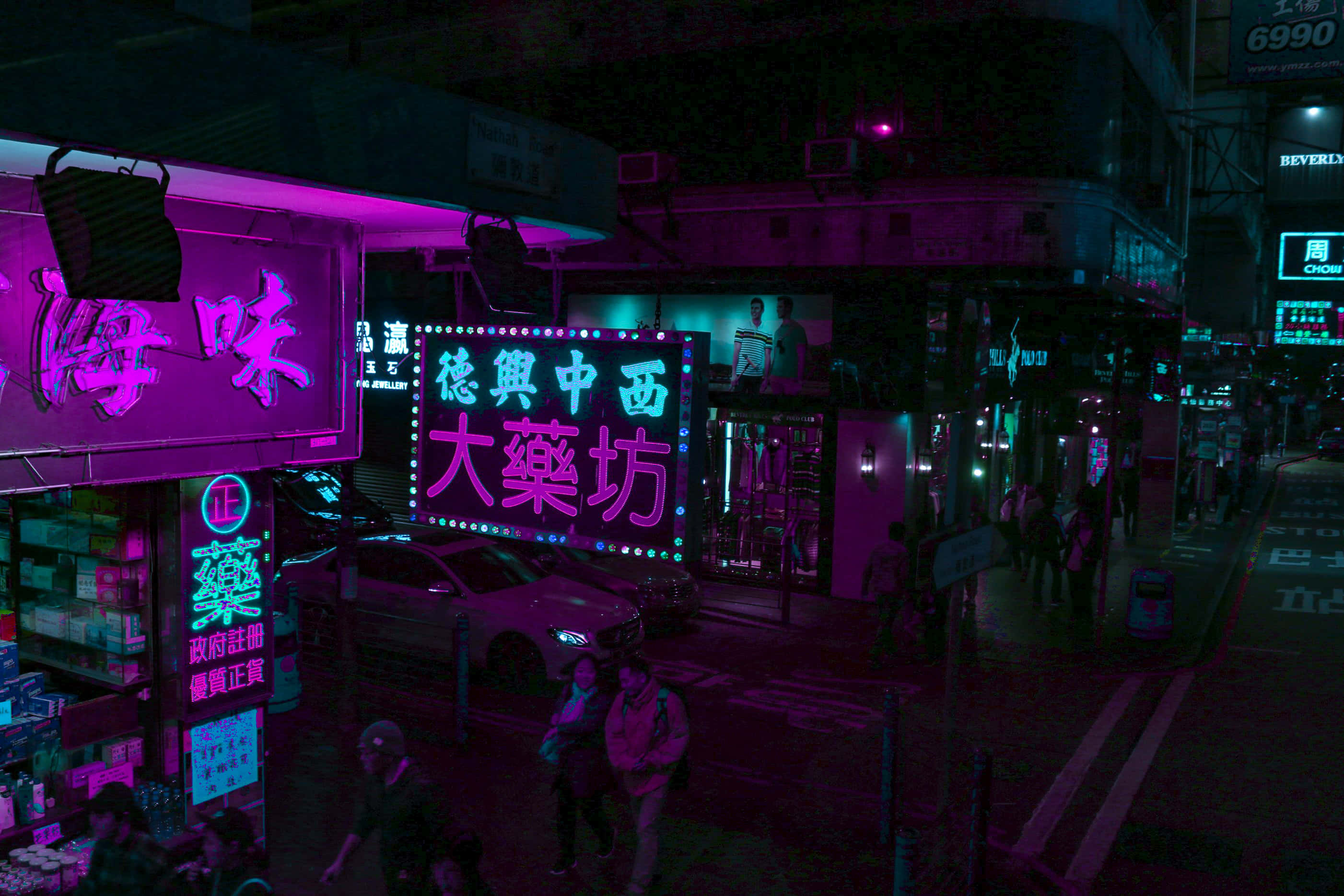 「與這款活力紫色霓虹美學電腦一起閃耀吧！」 壁紙 — 鮮豔的霓虹招牌在夜間繁忙的香港街道上閃耀著粉紅色和藍綠色，有行人和汽車。