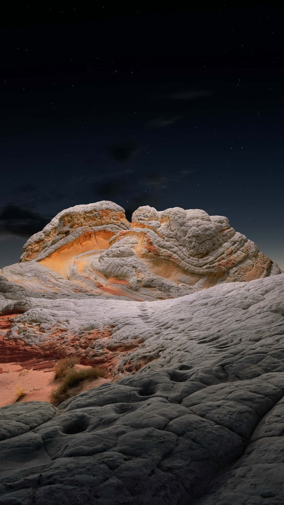 星空下，紋理豐富的岩層上閃爍著橙色和白色的層次。