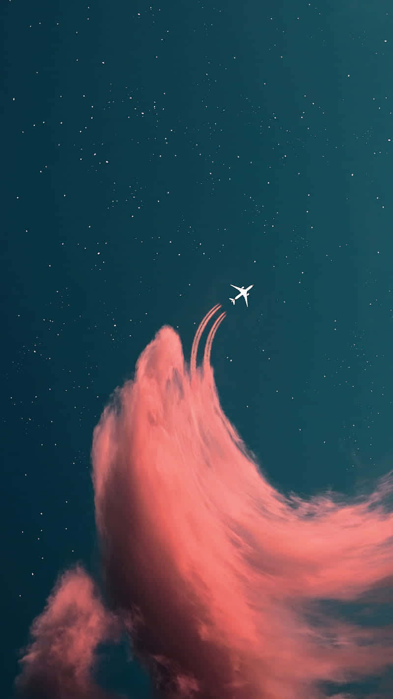 一架飛機在繁星點點的夜空中飛過粉紅色的雲層。