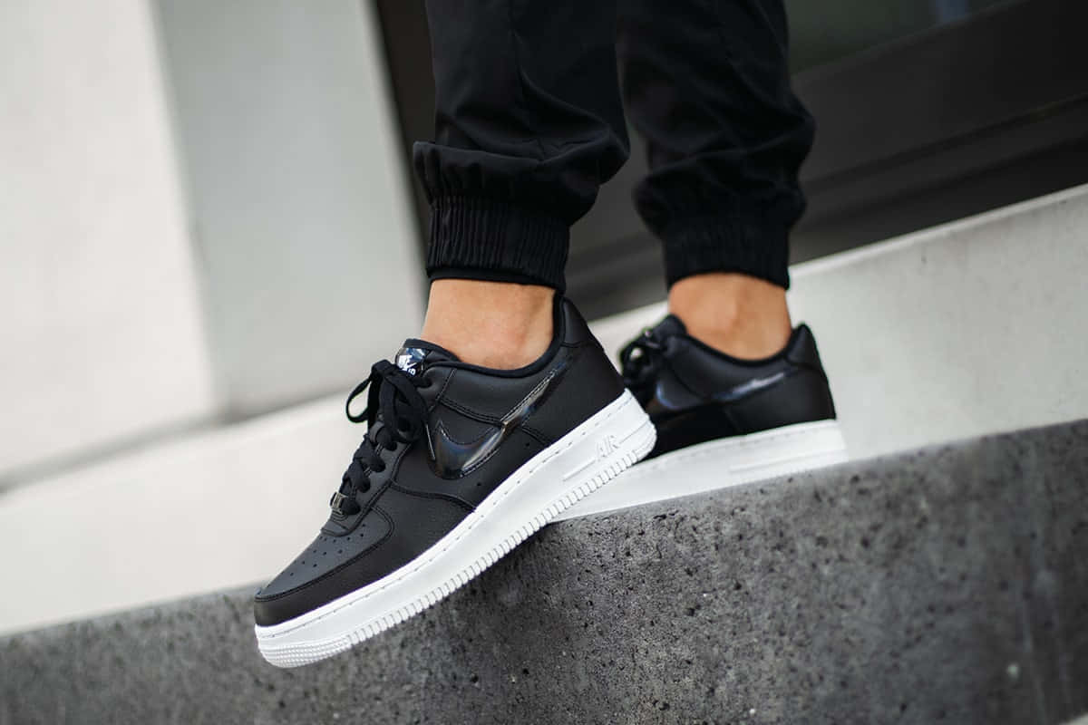 黑色Nike Air Force 1波鞋白色鞋底喺石屎級上。