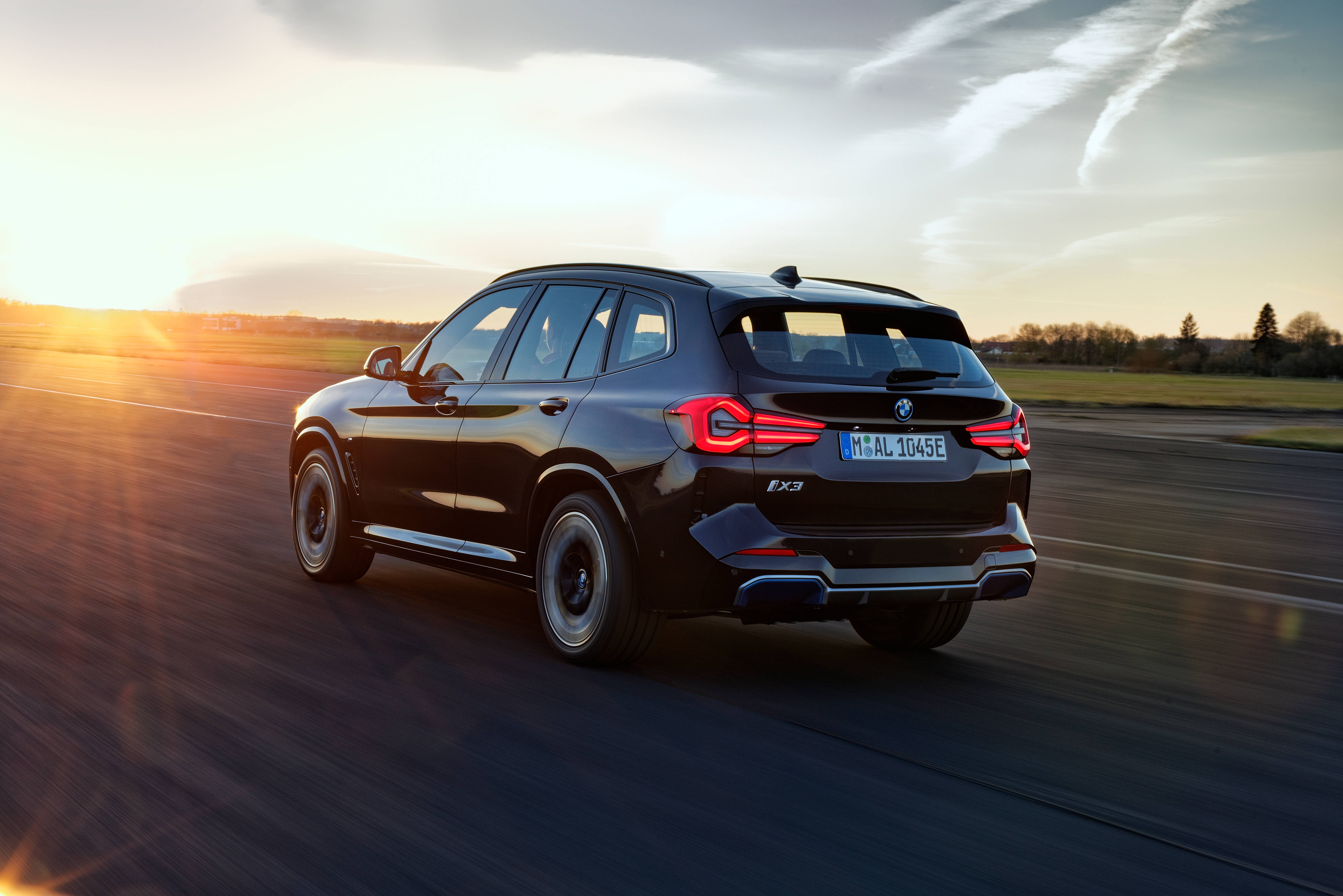 與黑色BMW同行 壁紙 — 一輛時尚的黑色BMW X3 SUV在日落時分行駛在高速公路上，地平線上的金色光芒閃耀。