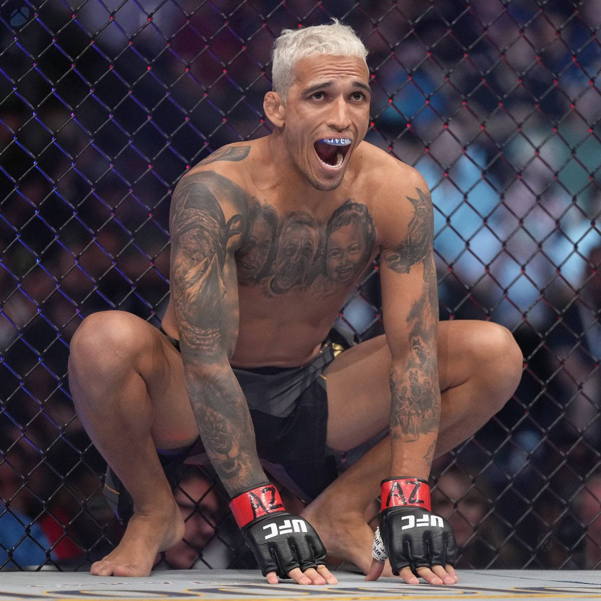 有紋身的MMA拳手在勝利後蹲在八角籠內。