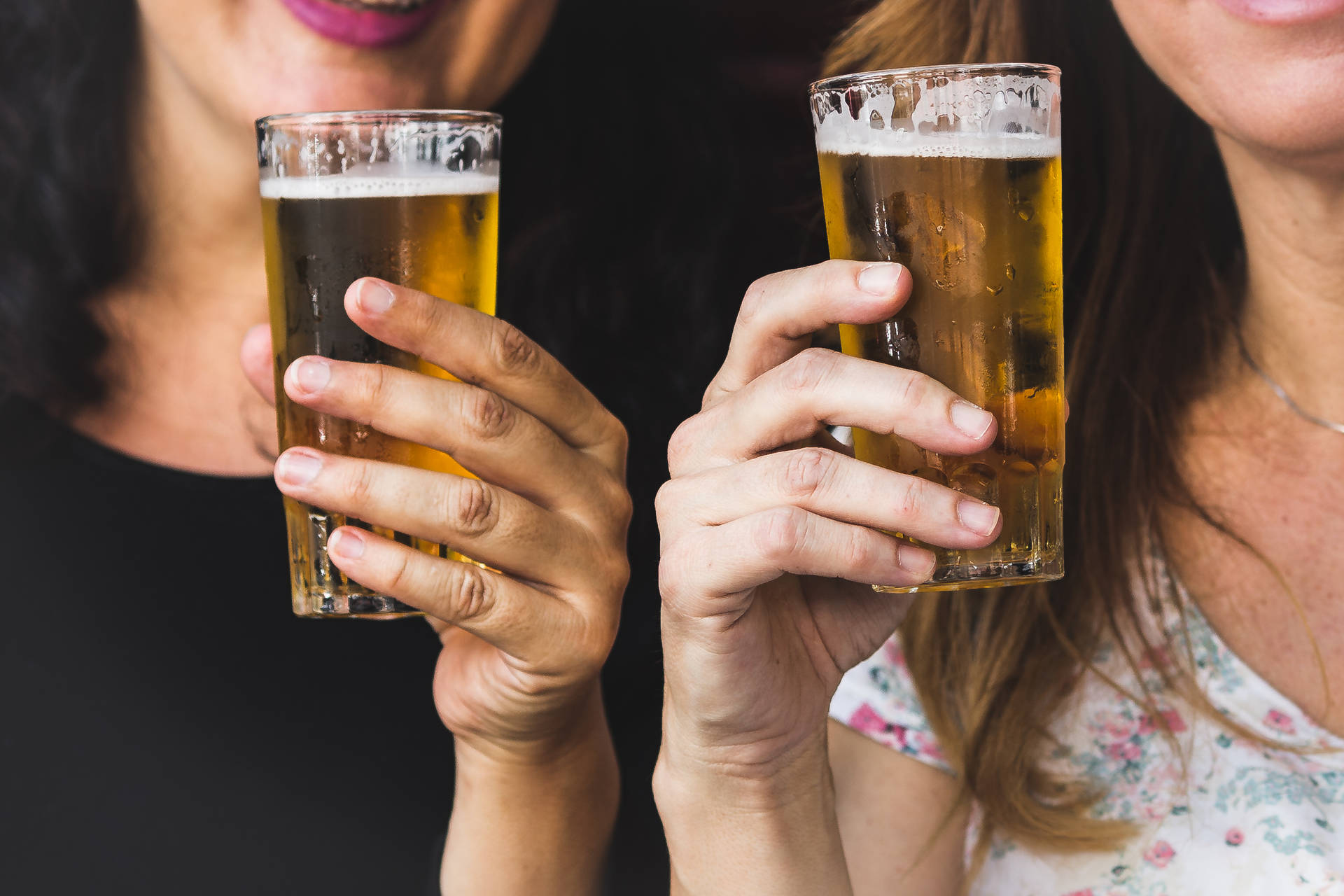 兩個女人微笑著用啤酒杯敬酒。