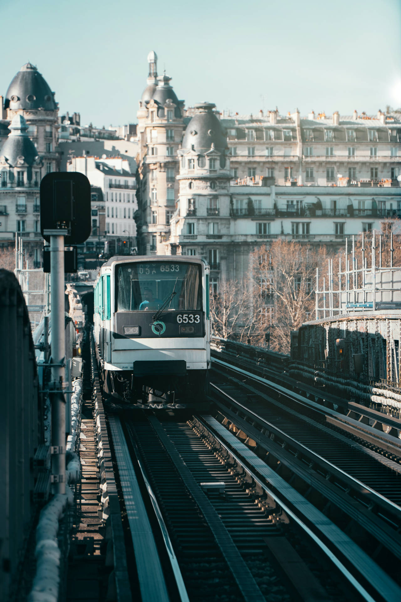 白色巴黎地鐵列車在高架軌道上，背景有歷史建築。