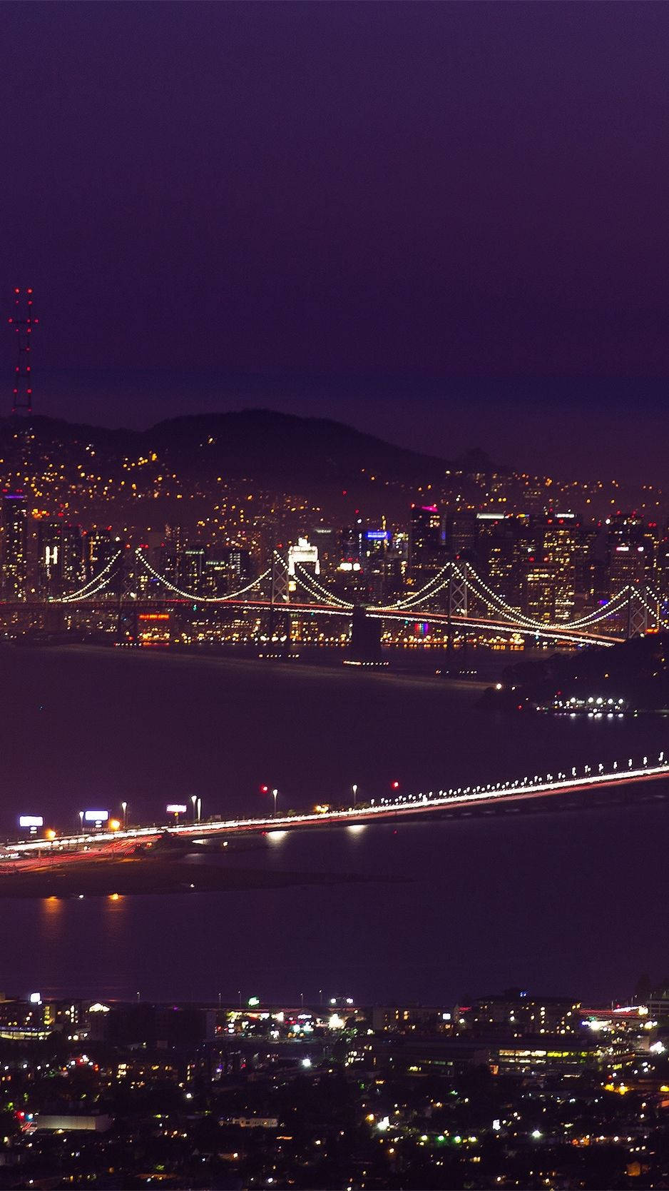橋樑和燈光在水面和山丘上閃爍的夜晚城市。
