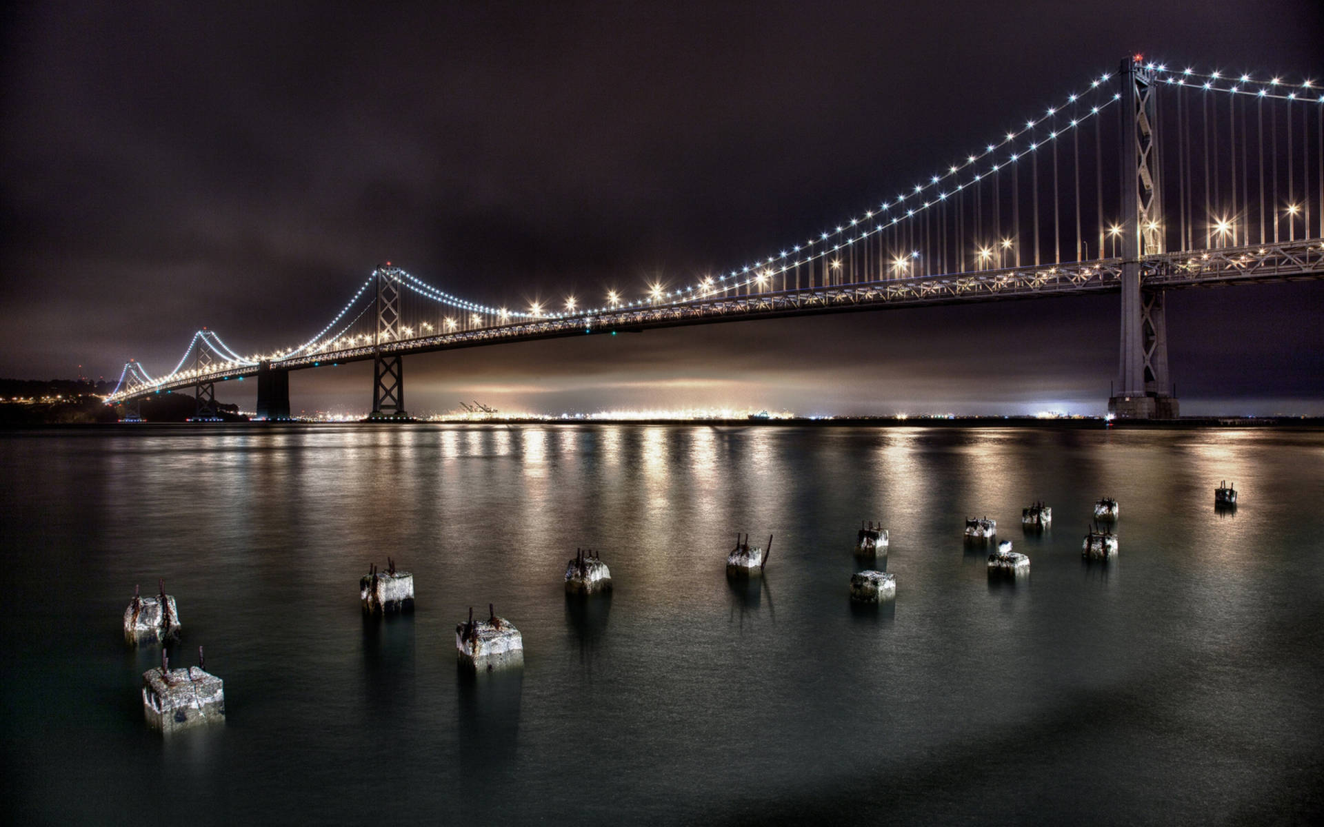 夜間發光的吊橋，平靜水面上有浮動平台。