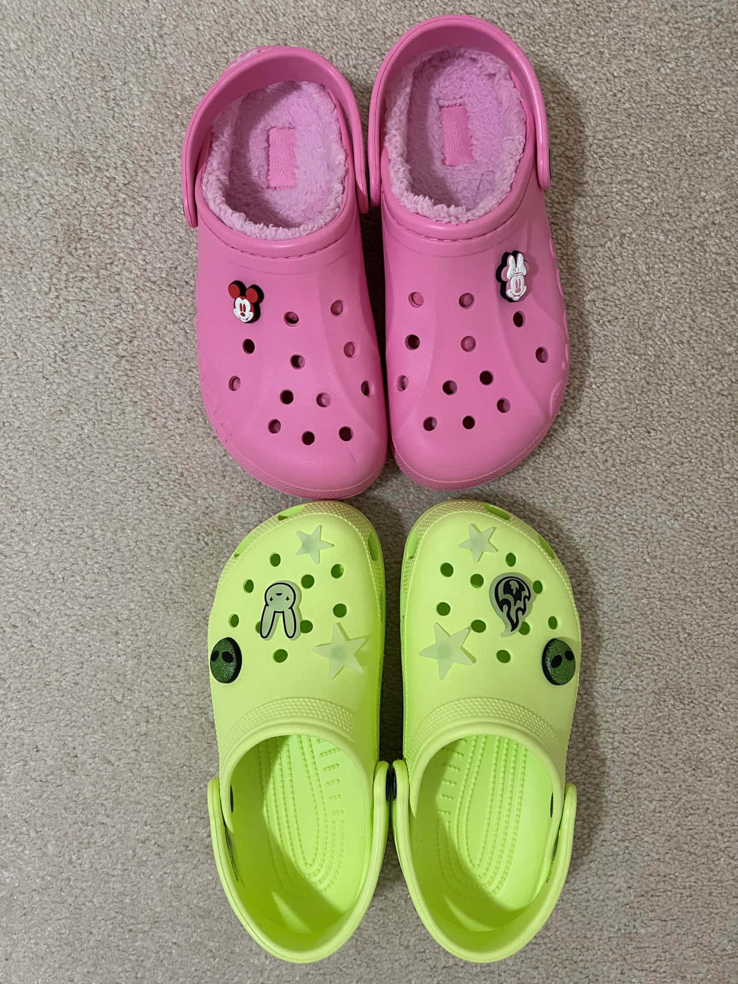 兩對兒童Crocs鞋，帶有角色飾物，放在地毯上。