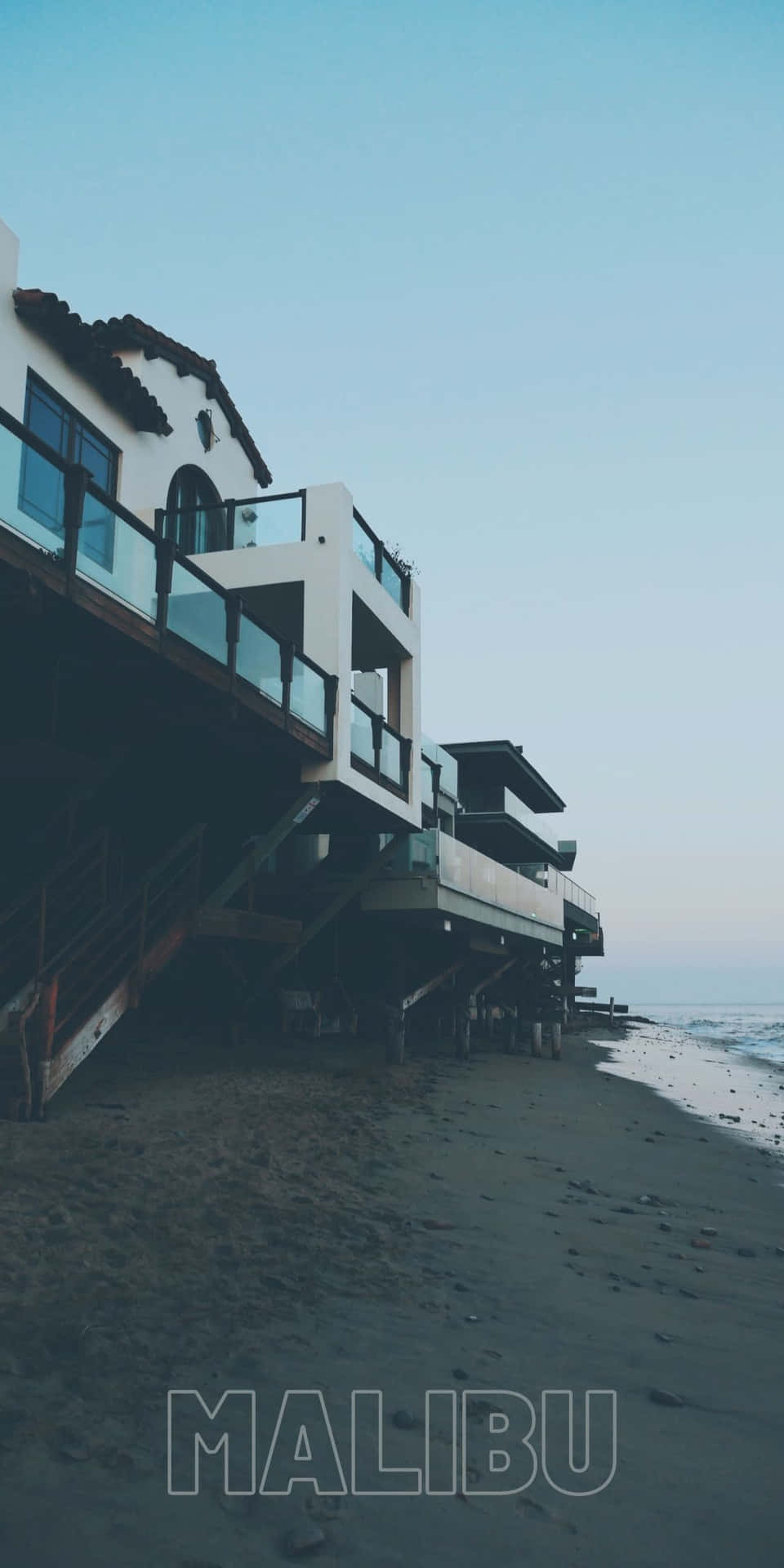 黃昏時分，高蹺上的現代海灘房屋與海浪