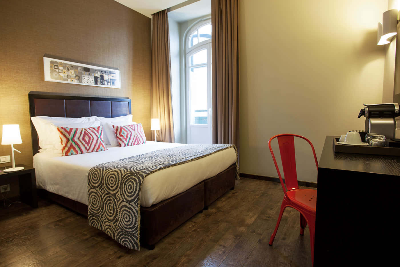 Hotel Room 桌布 壁紙 — 舒適的酒店客房，整齊的床鋪、紅色椅子、木地板，以及床頭燈的溫暖燈光。