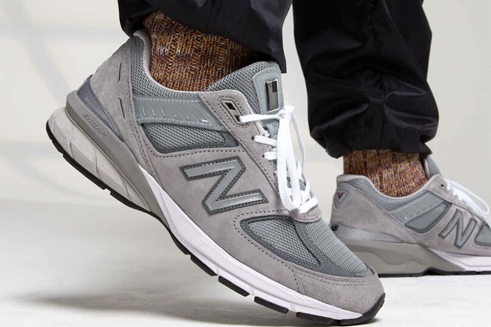 灰色New Balance運動鞋配白色鞋帶和圖案襪子。