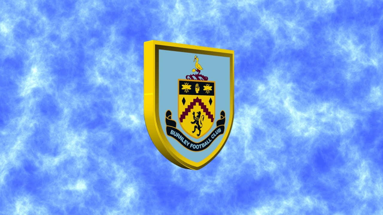 Burnley Fc 桌布 壁紙 — 般尼足球會徽章在充滿活力的藍色多雲天空中飄浮，帶有金色邊框和詳細的紋章符號。