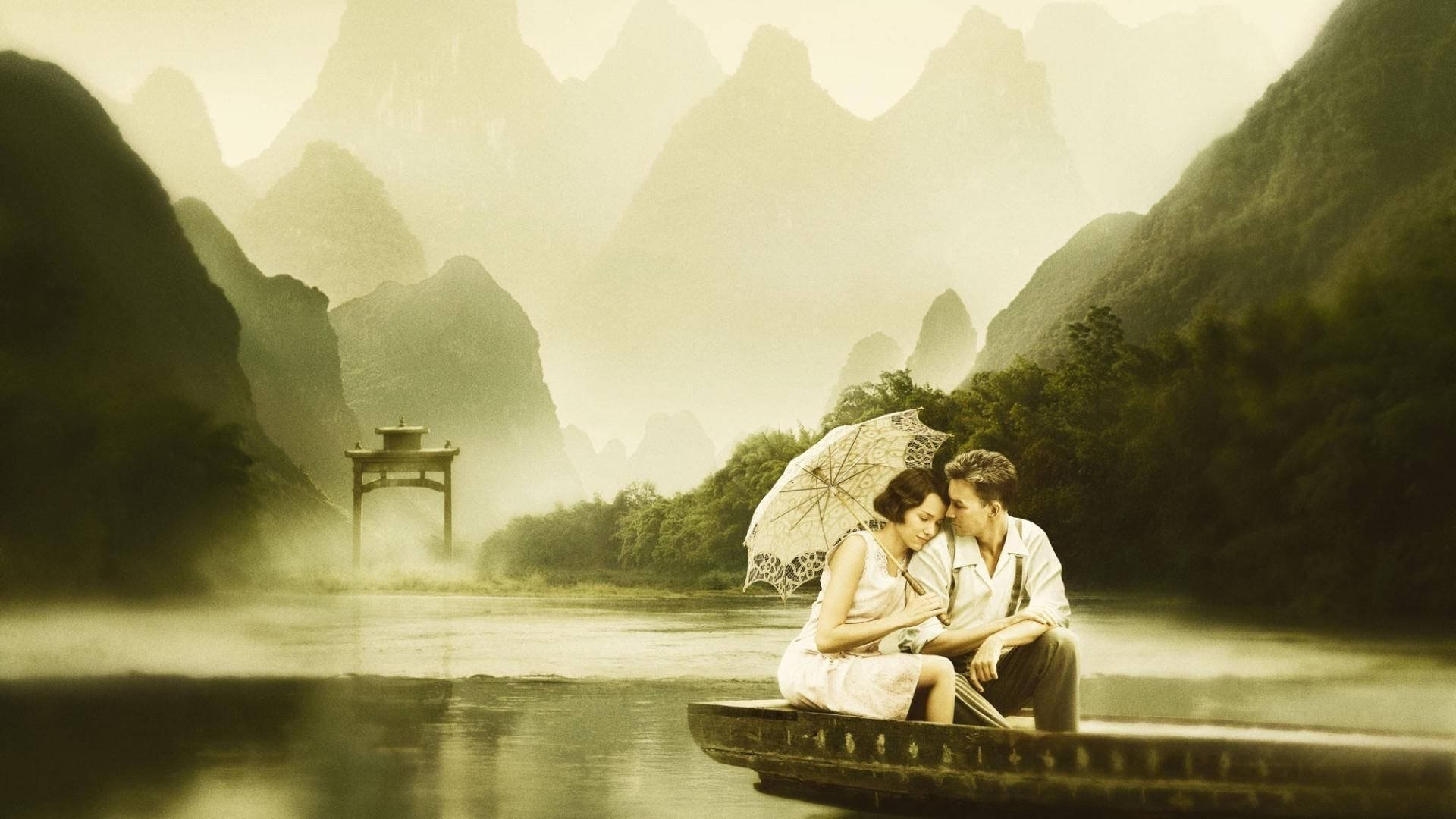 船上的愛情故事 壁紙 — 一對情侶在霧氣瀰漫的河上，在船中撐傘共享親密時刻，四周環繞著高聳的喀斯特山峰。