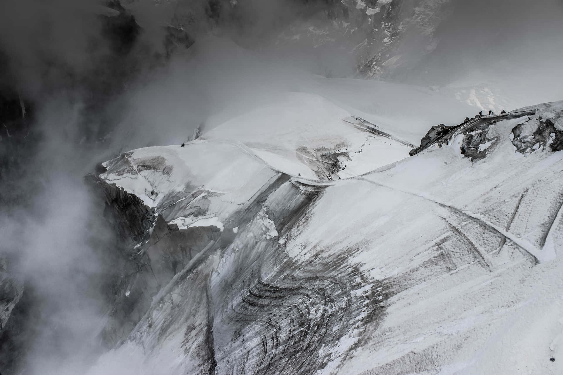 登山者穿越被迷霧籠罩的雪山脊。